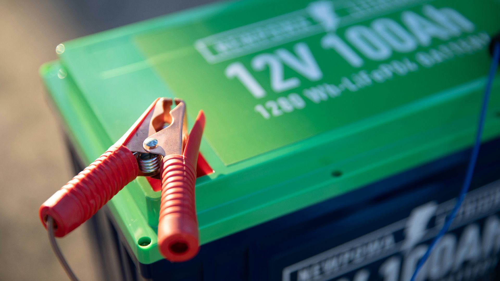 a red and green battery with a pair of pliers attached to it