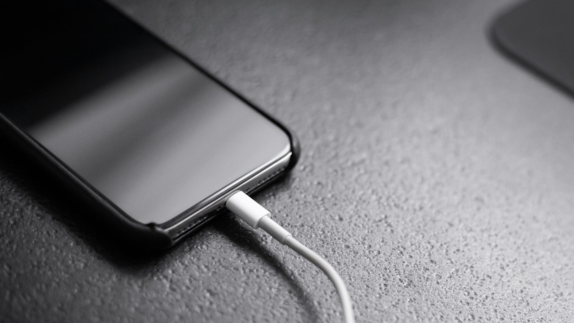 black smartphone with charger cord connected