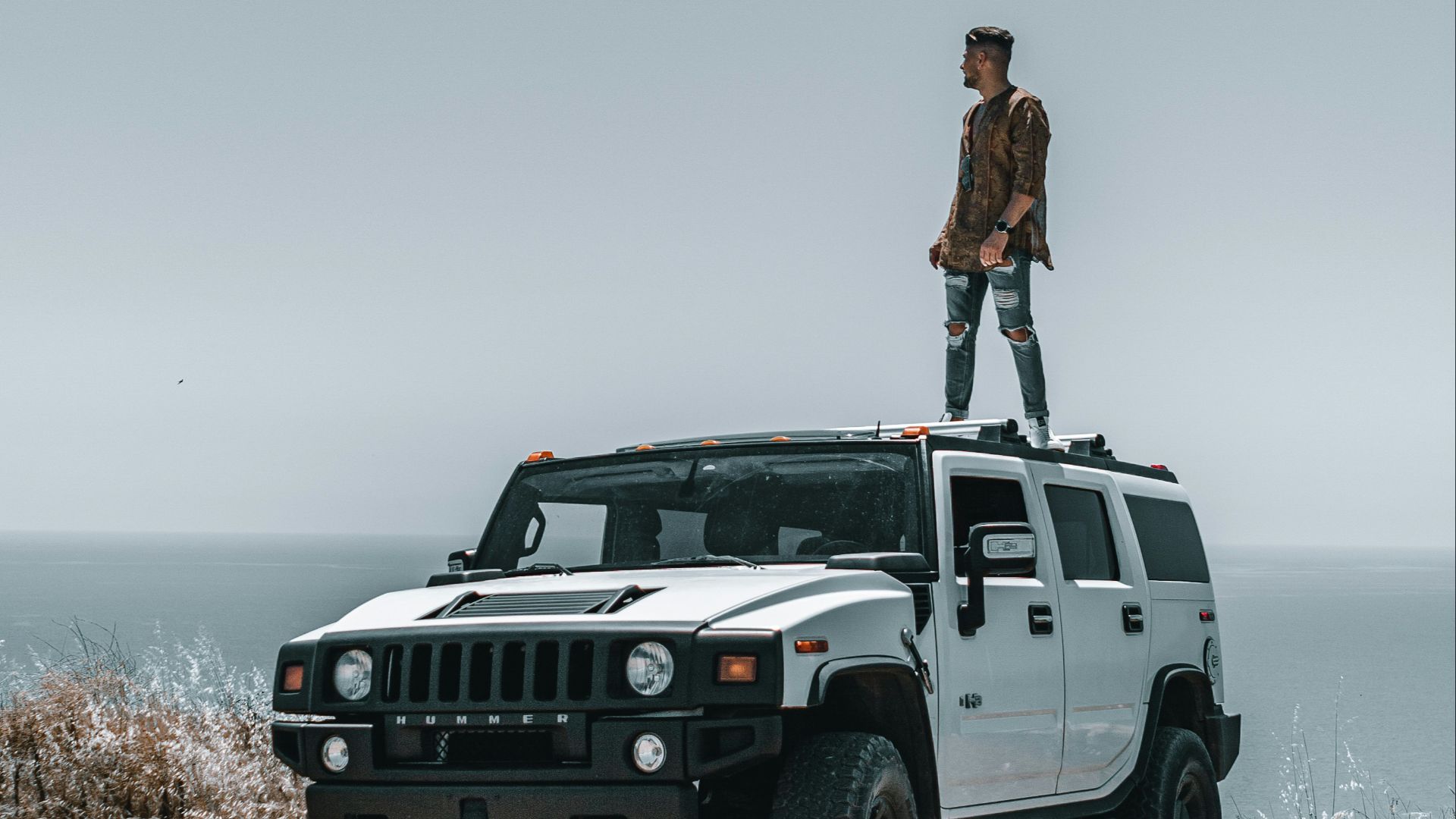 a man standing on top of a white hummer truck