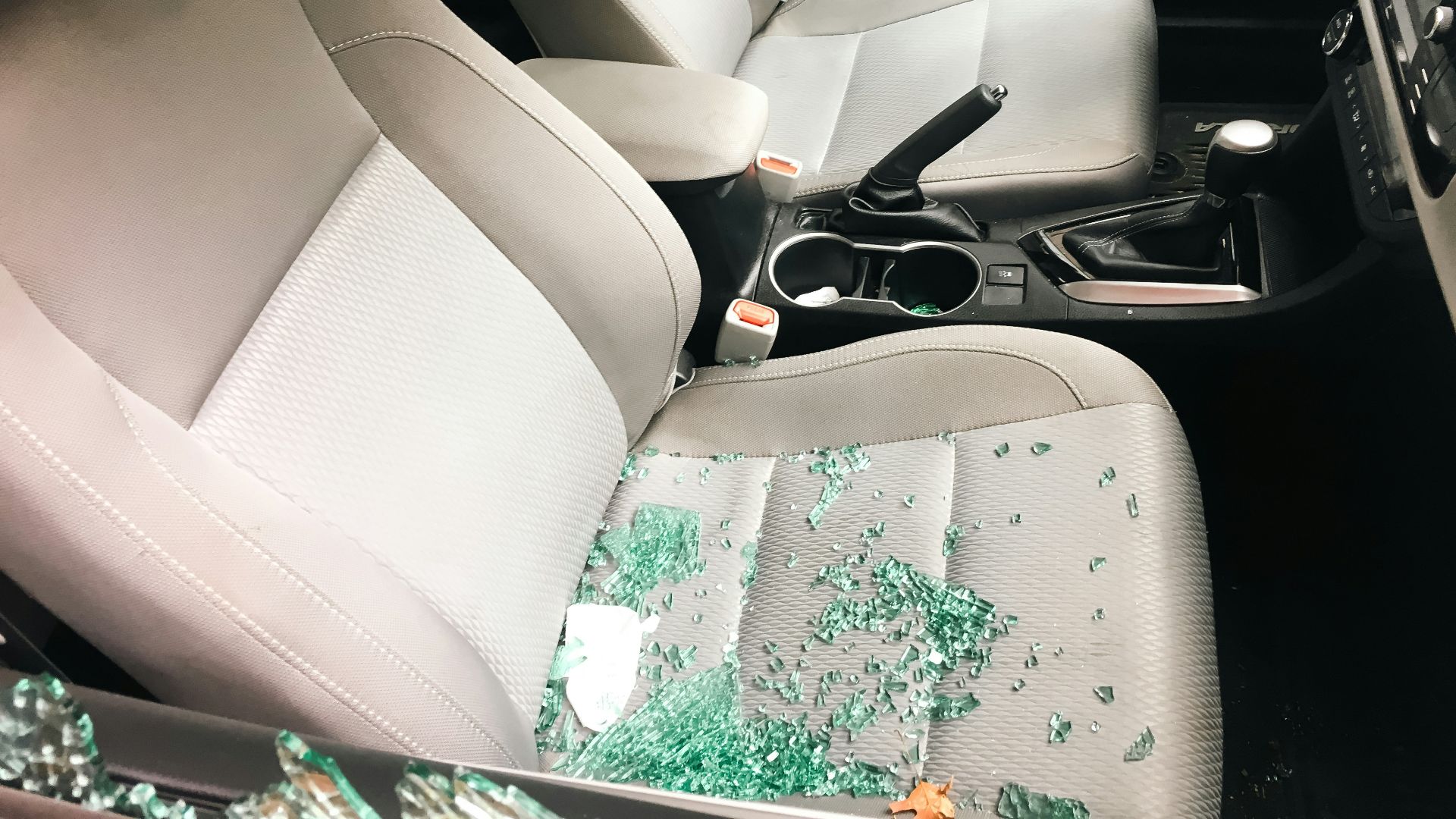 Car interior with shattered glass from a broken window.