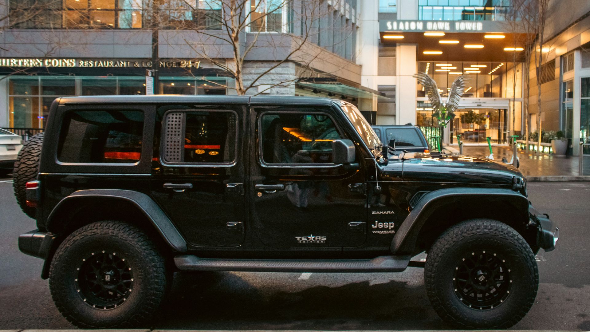 A black jeep sits in front of a building.