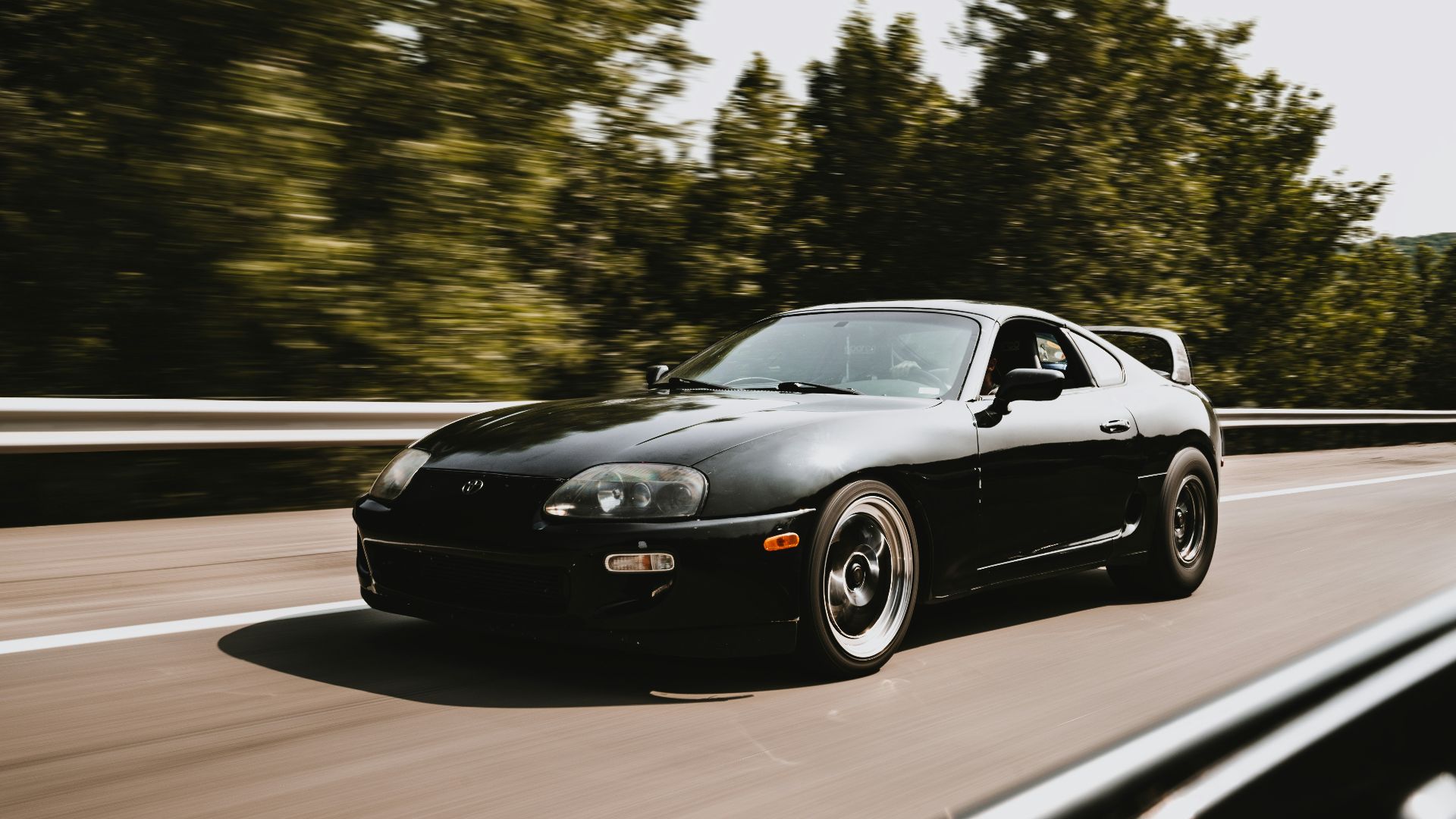 a black sports car driving down the road