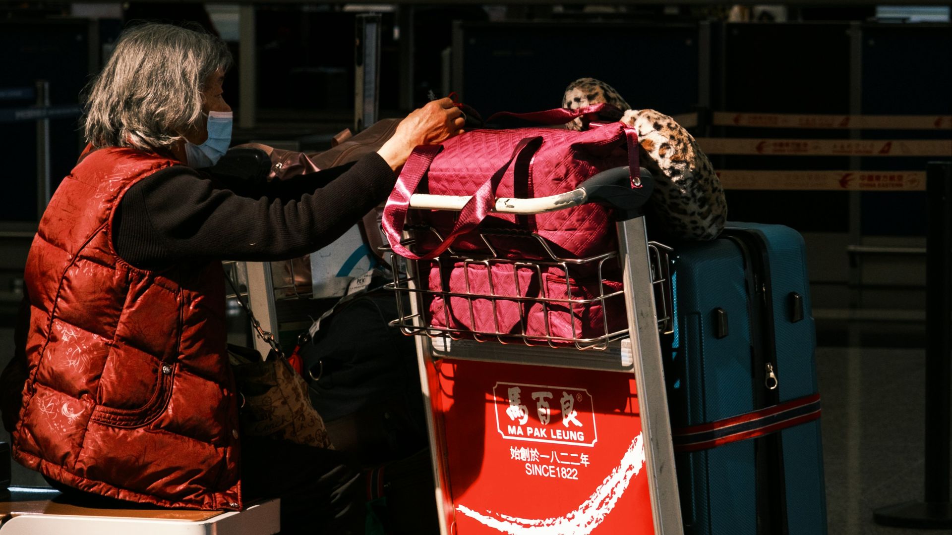 a woman sitting in a chair next to a luggage cart