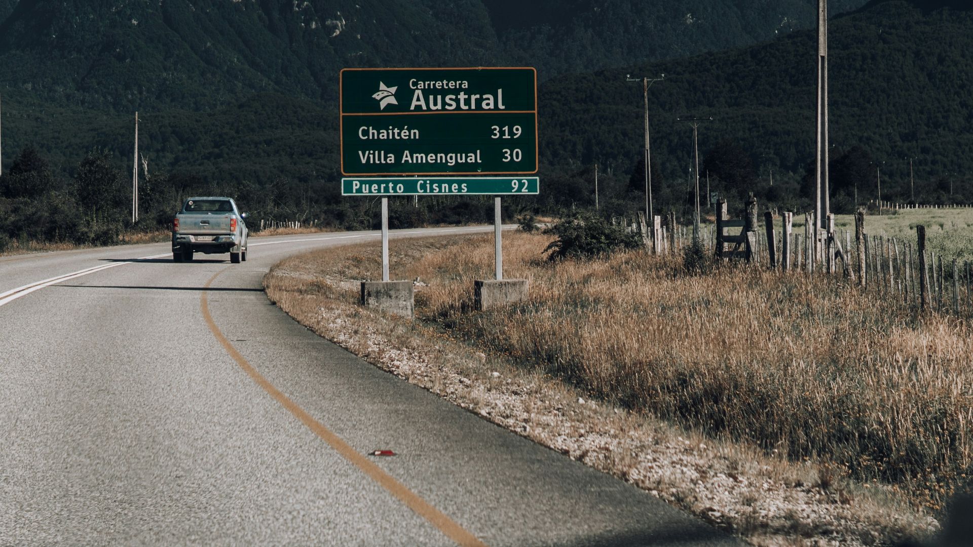 a car driving down a road with a mountain in the background