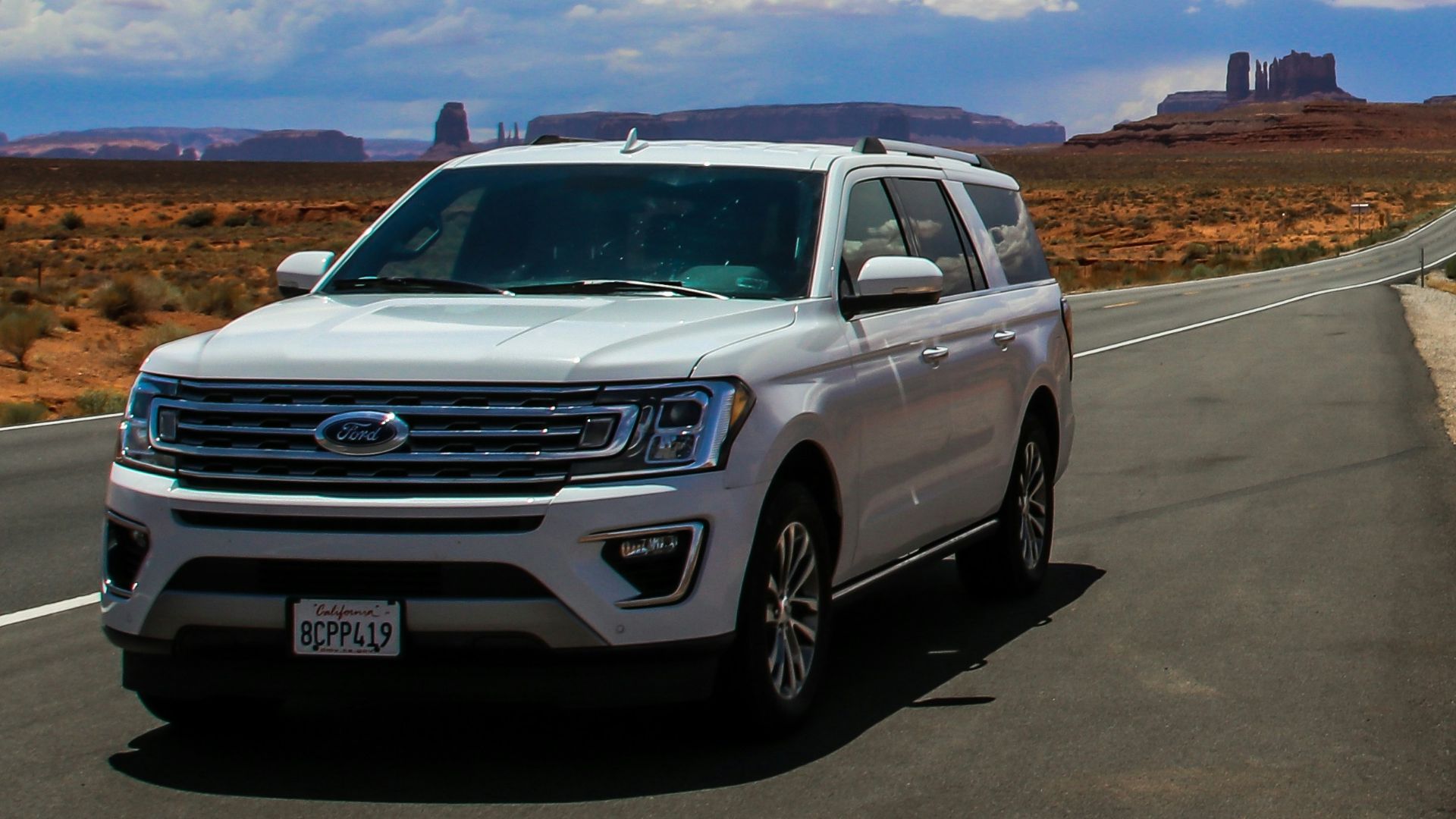 a white suv driving down a desert road
