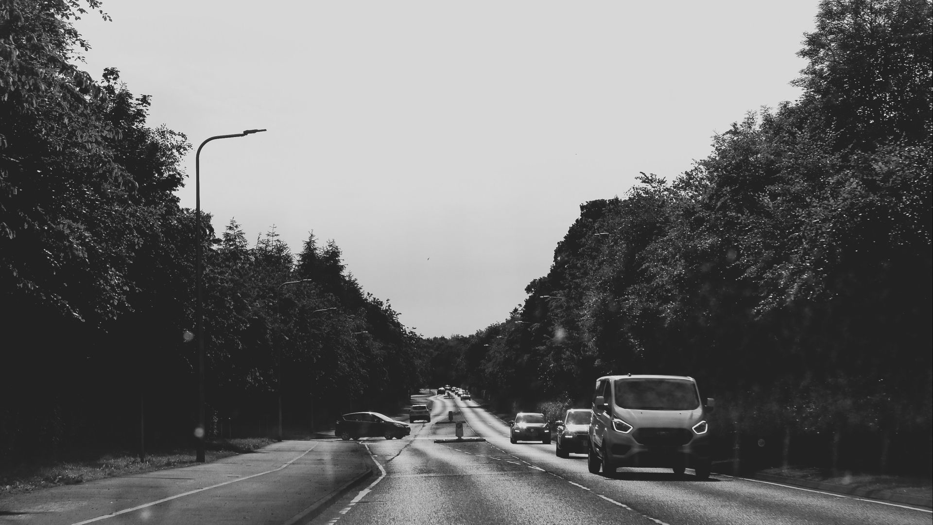 a black and white photo of cars driving down a road