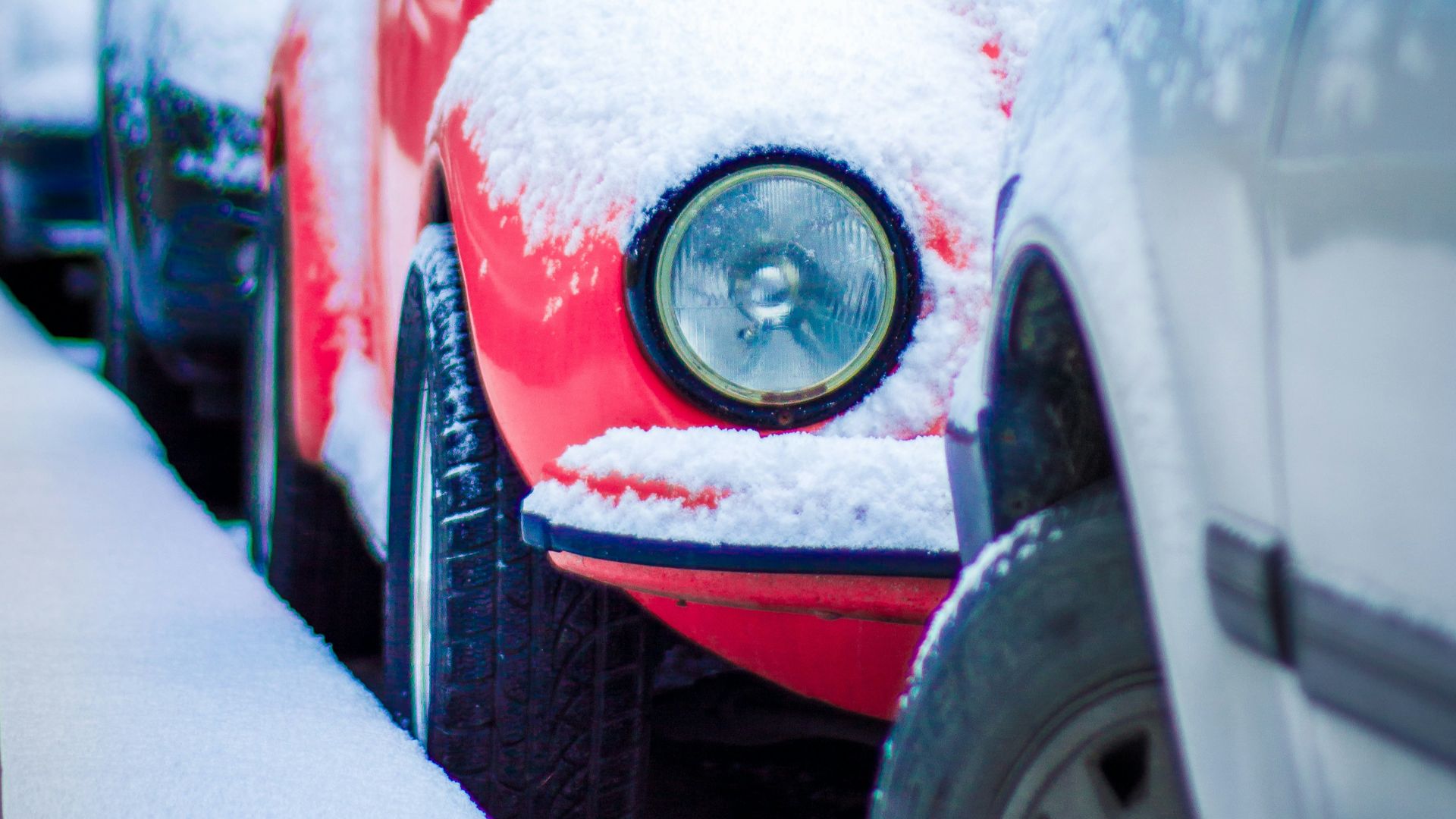 a row of parked cars covered in snow