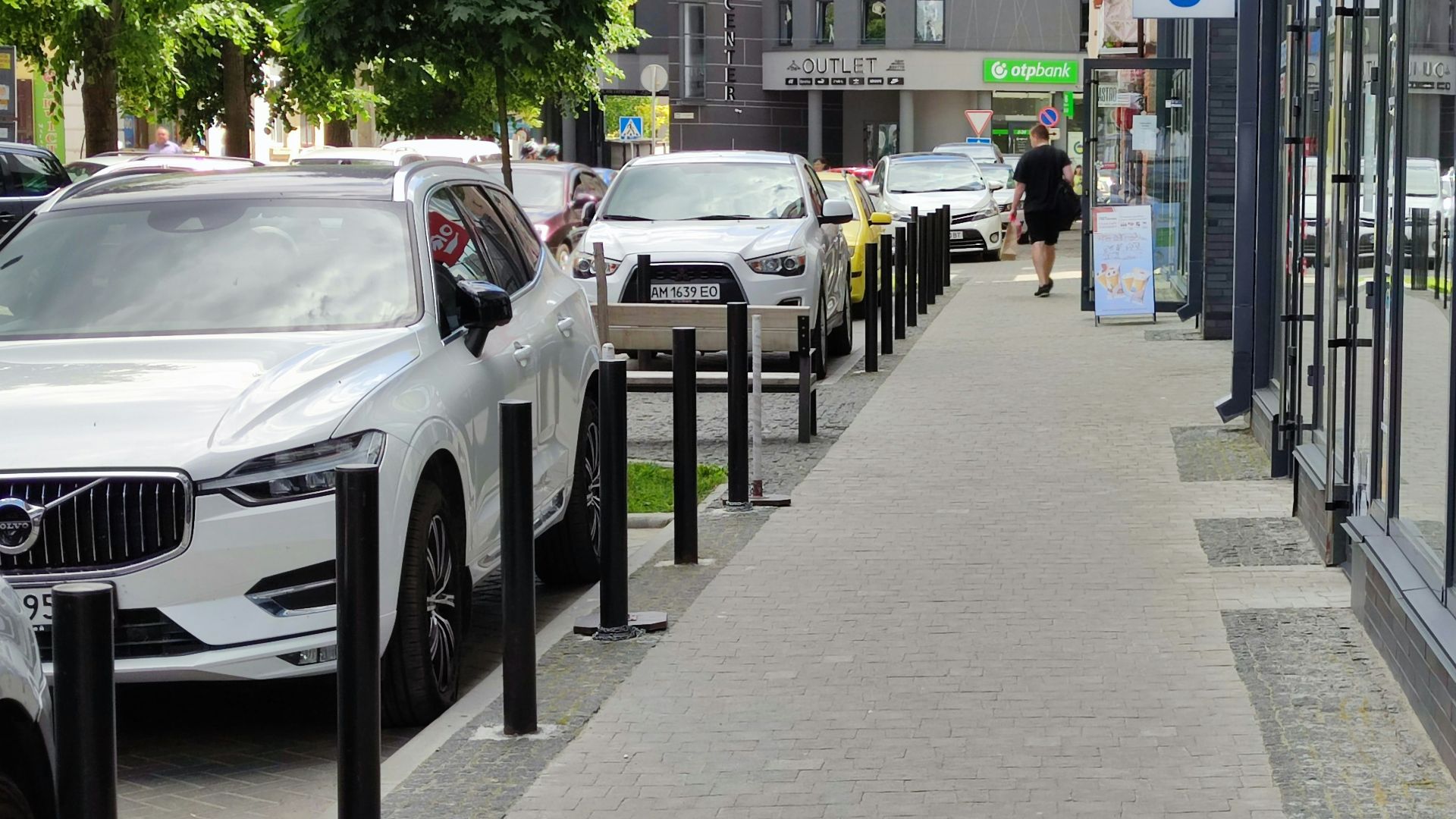 a row of parked cars sitting next to a sidewalk