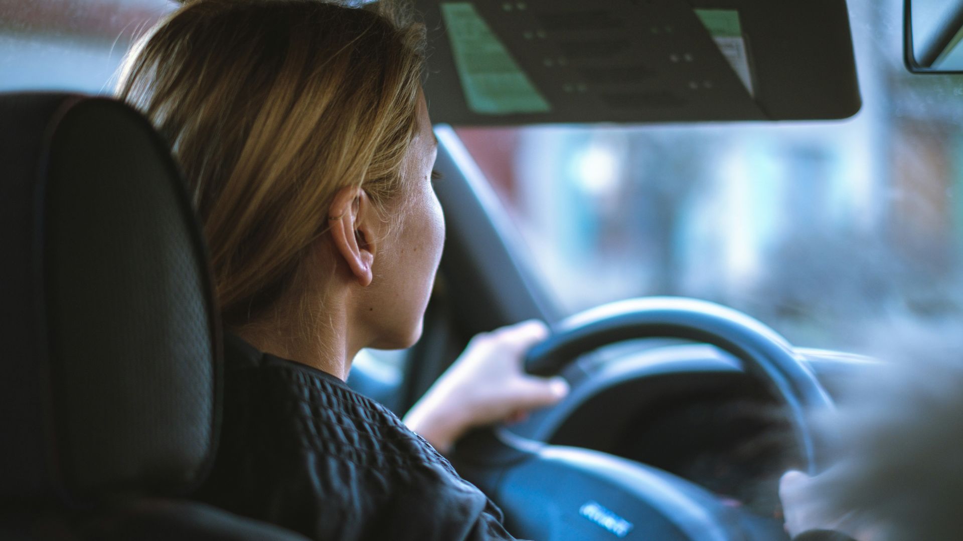 a woman sitting in a car with a steering wheel