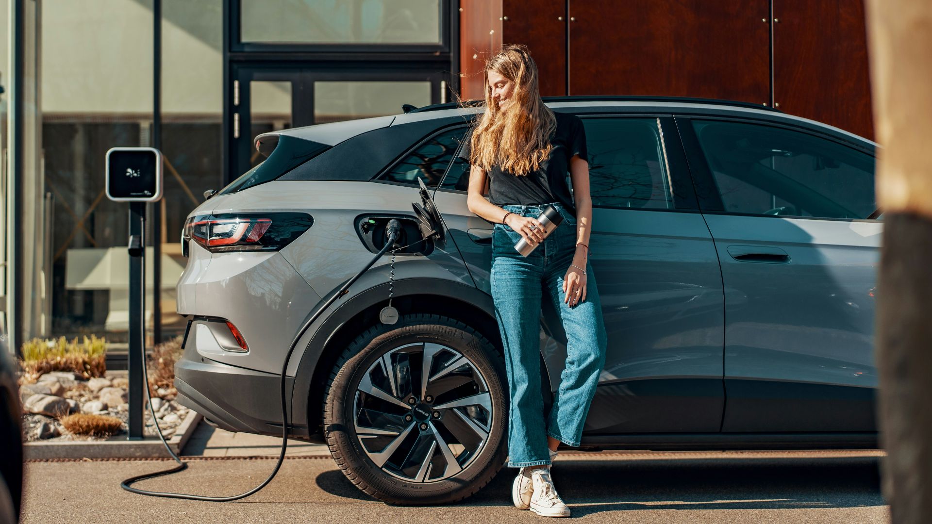 a woman standing next to a blue car
