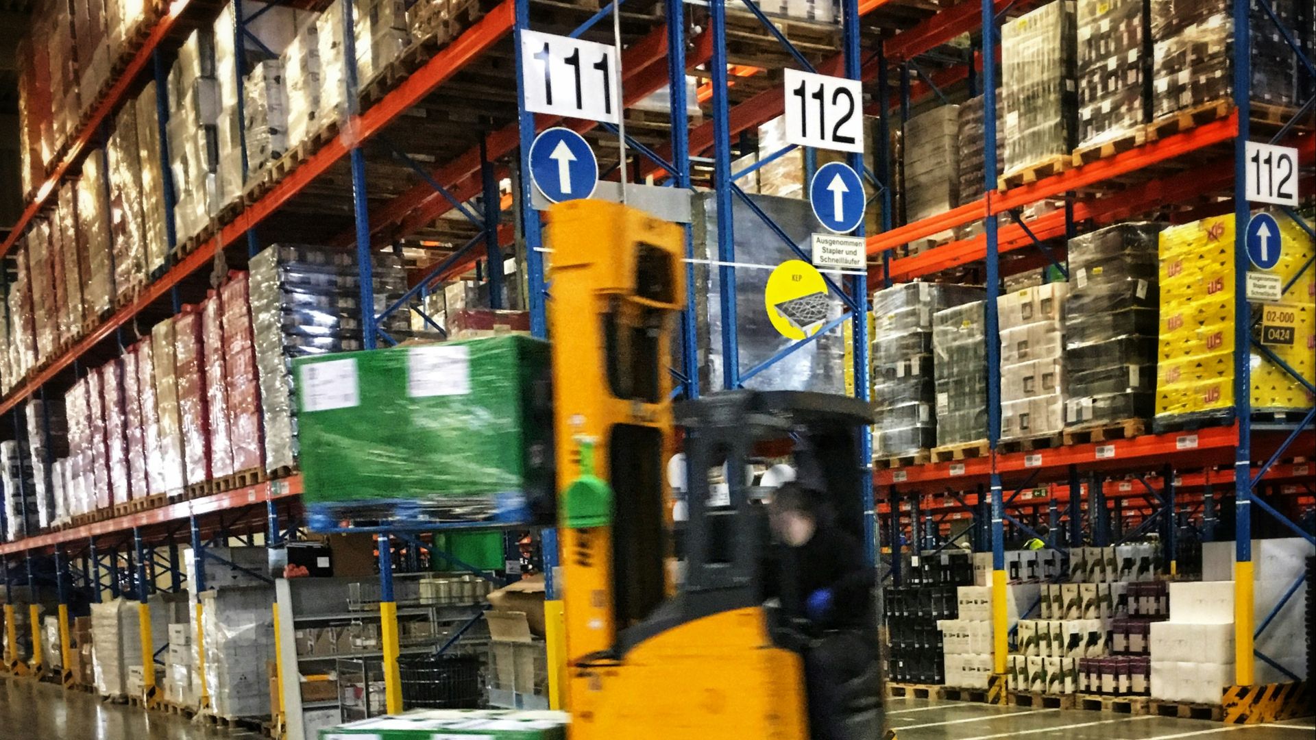 a forklift driving through a warehouse filled with pallets