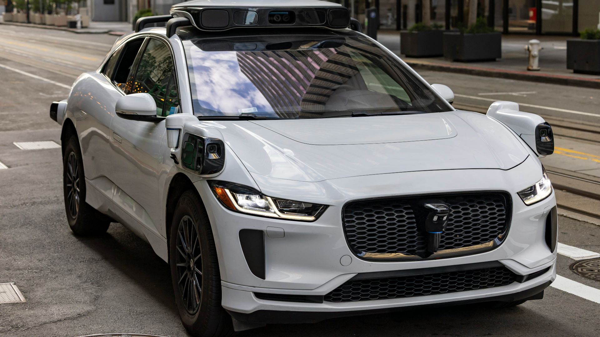 A white self-driving car on a city street.