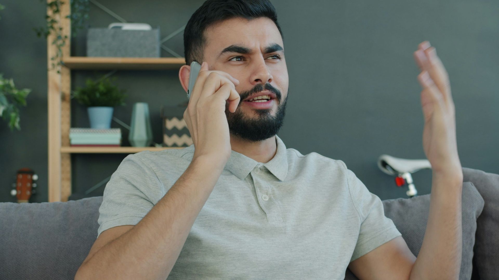 Man talking animatedly on the phone while sitting on couch.