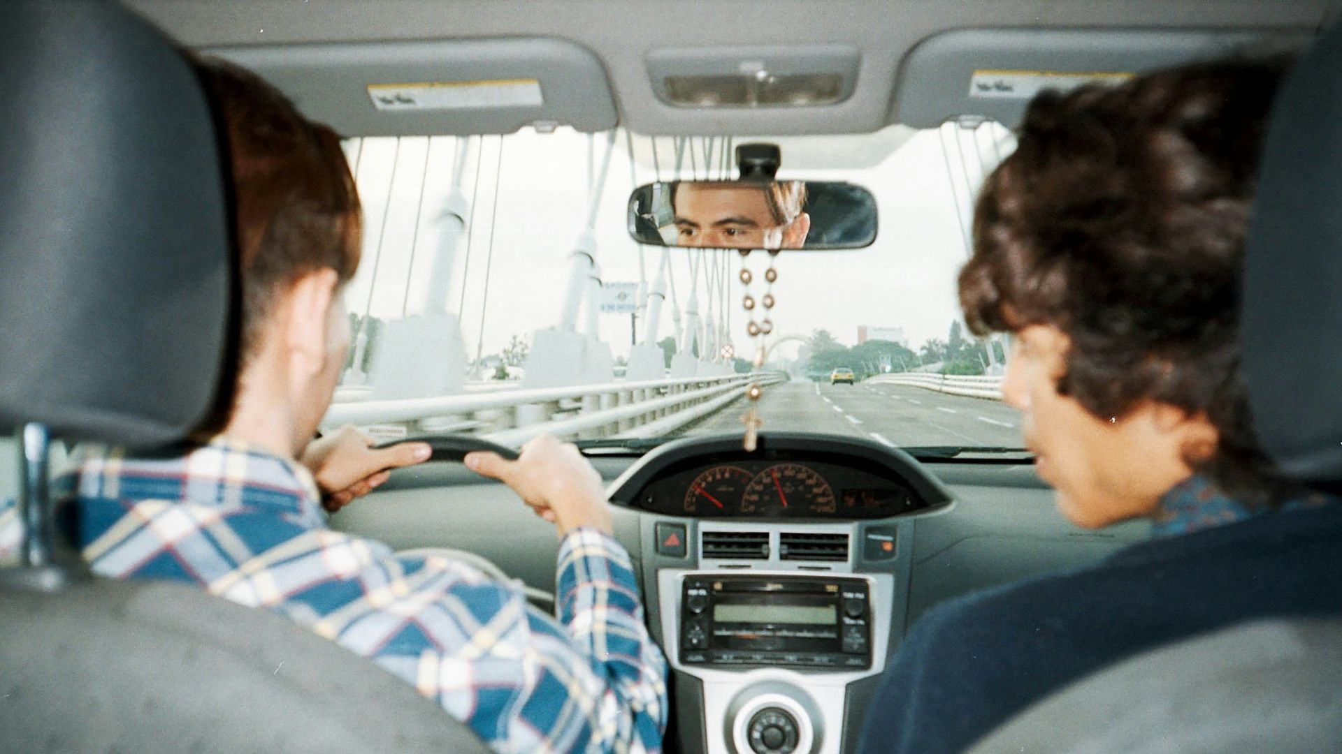 A man driving a car with another man in the back seat