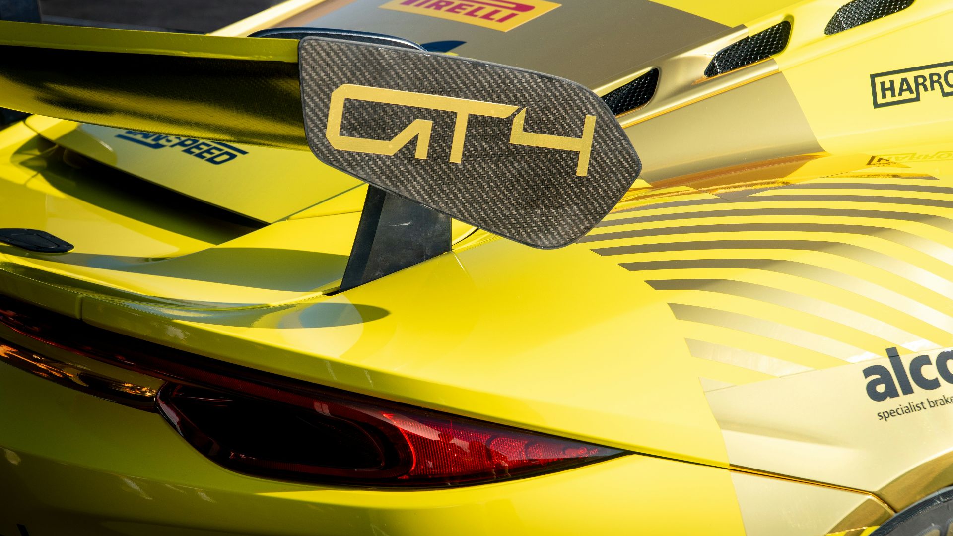 A yellow gt4 racing car's spoiler is visible.