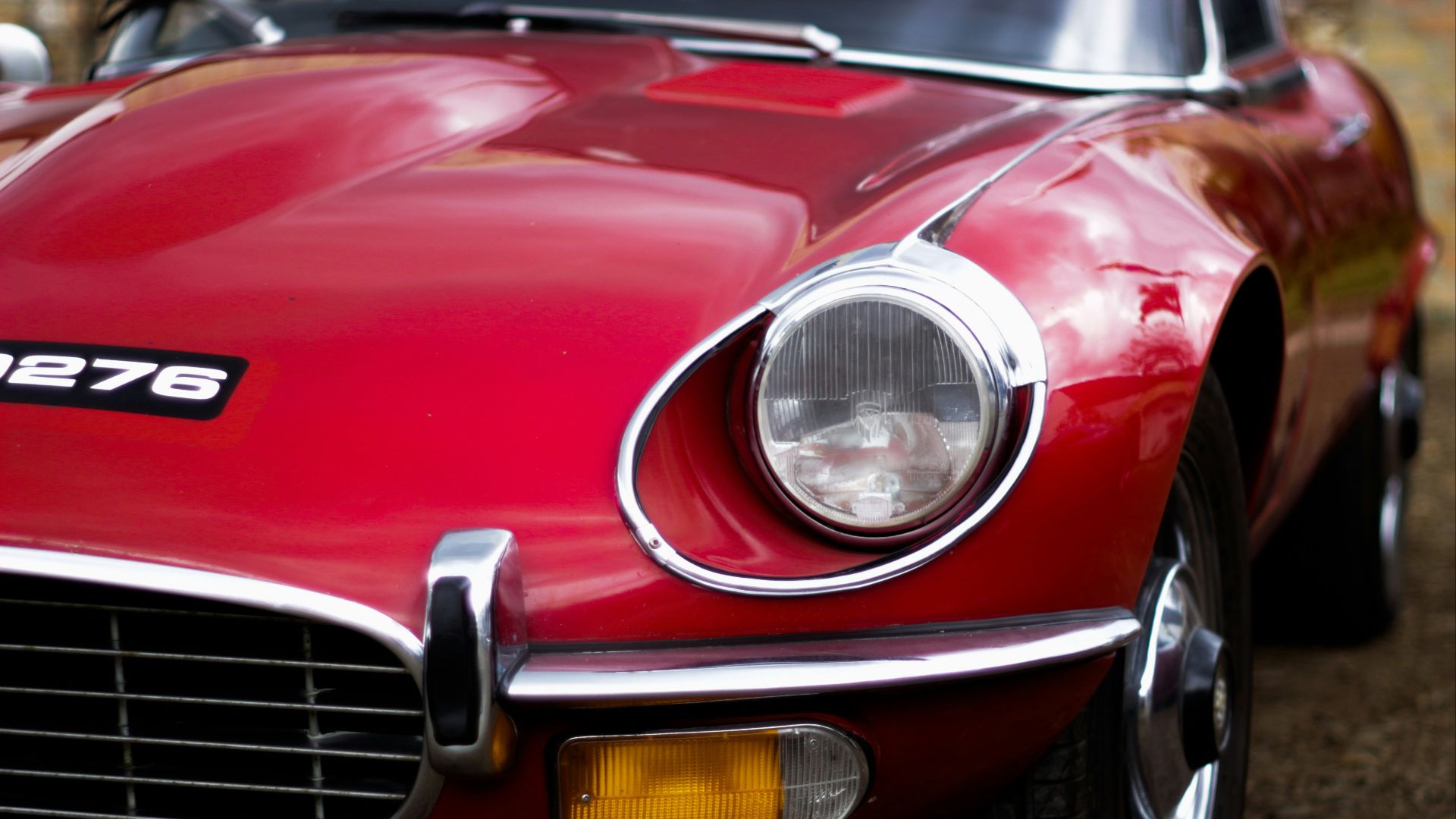 red coupe parked on brown soil