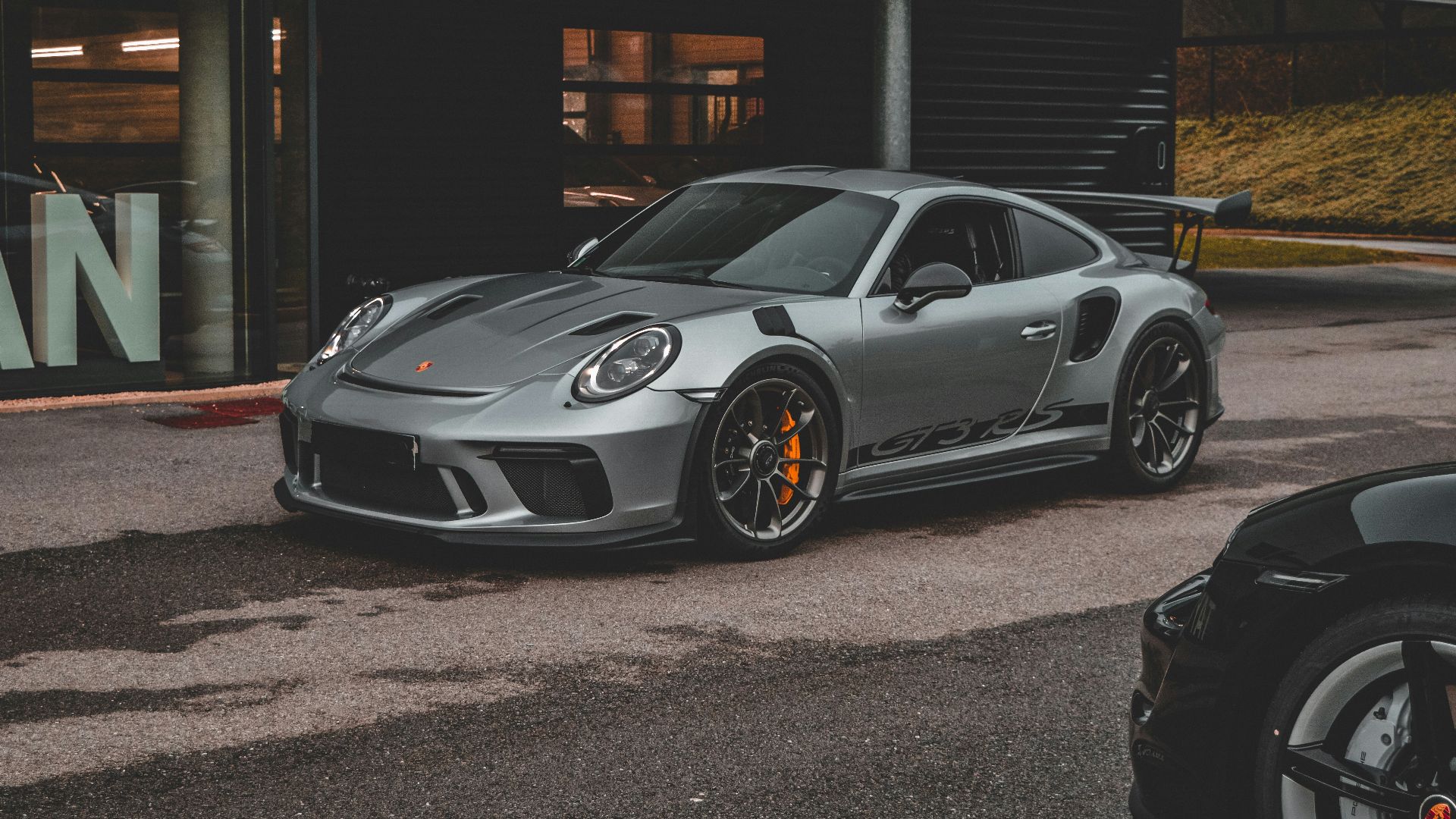 a grey porsche gtr parked in front of a building