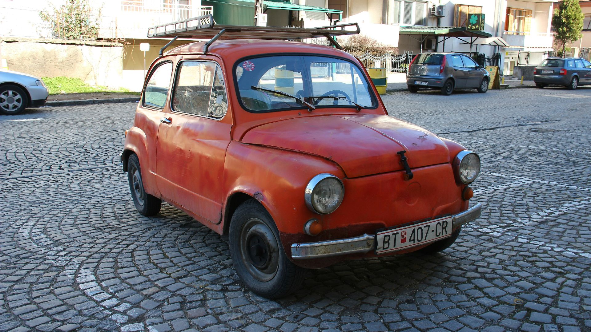 red volkswagen beetle parked on street during daytime