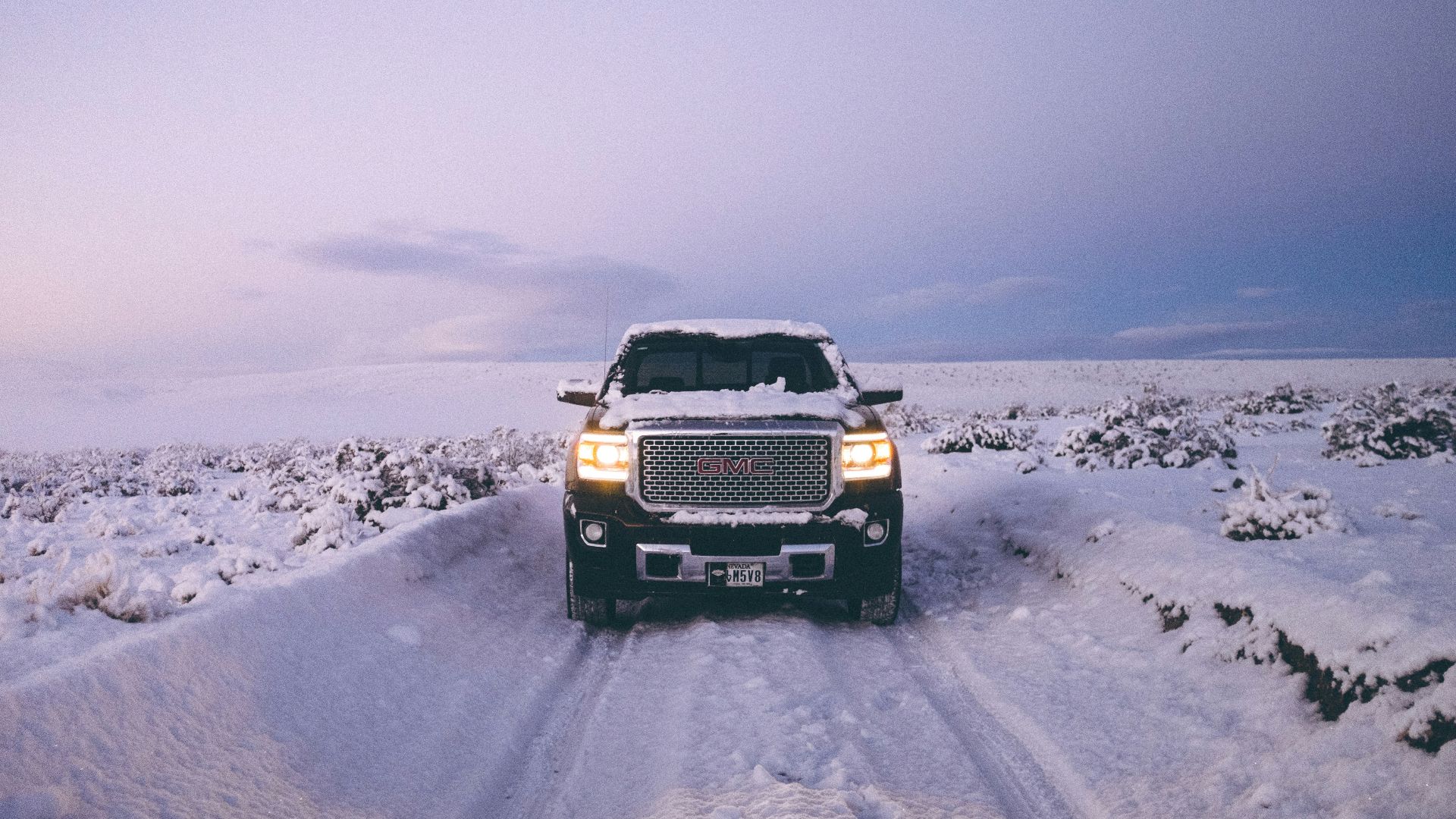 black GMC Sierra Denali on snow covered road