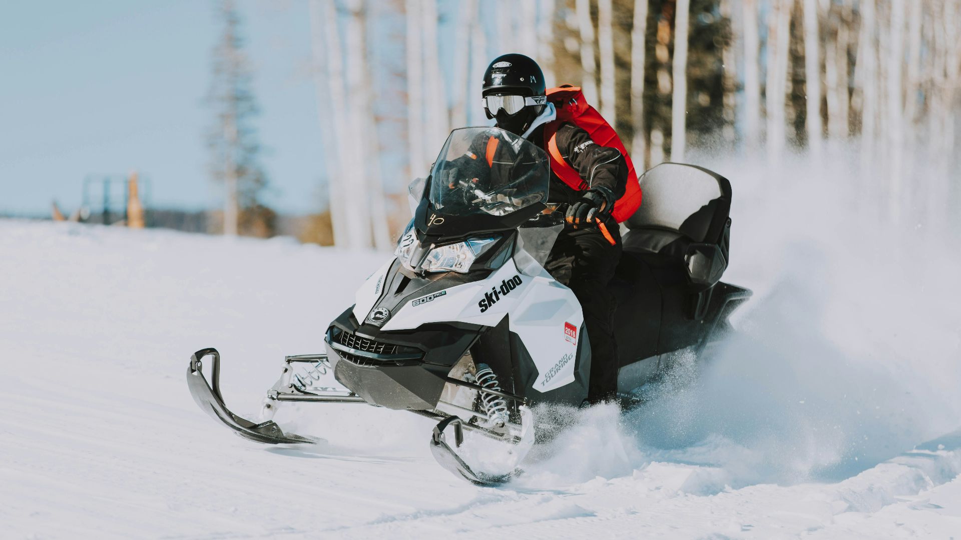 snowmobile speeding on snow near tree lines