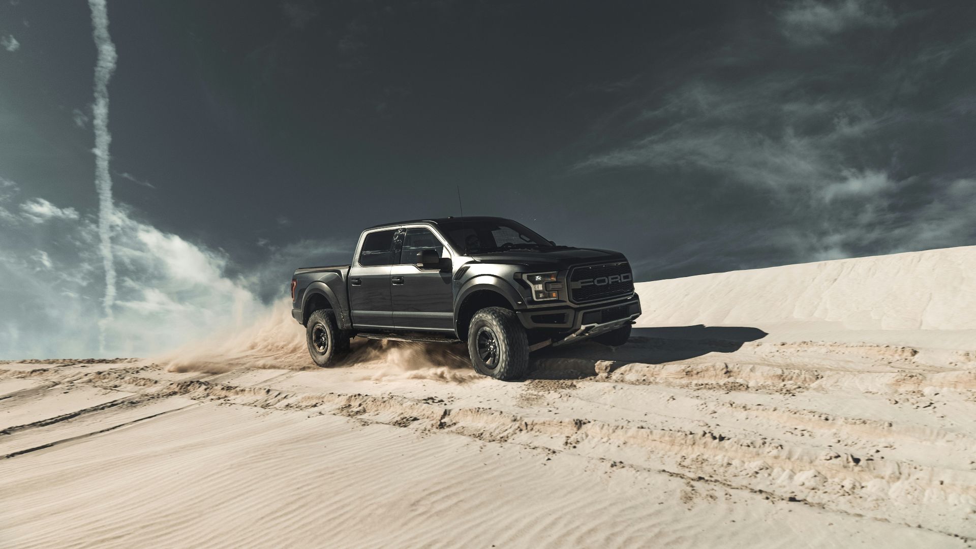 black chevrolet crew cab pickup truck on brown sand under blue sky during daytime
