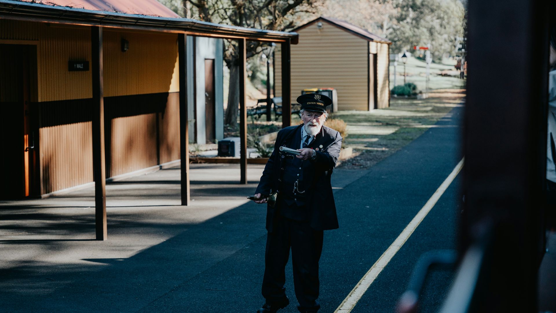 A man standing on the side of a road next to a train