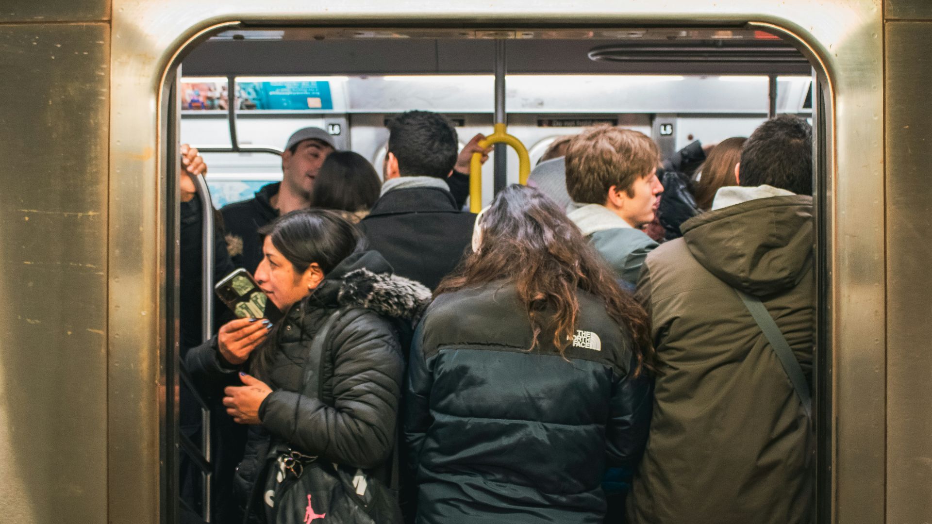 People are packed tightly in a subway car.