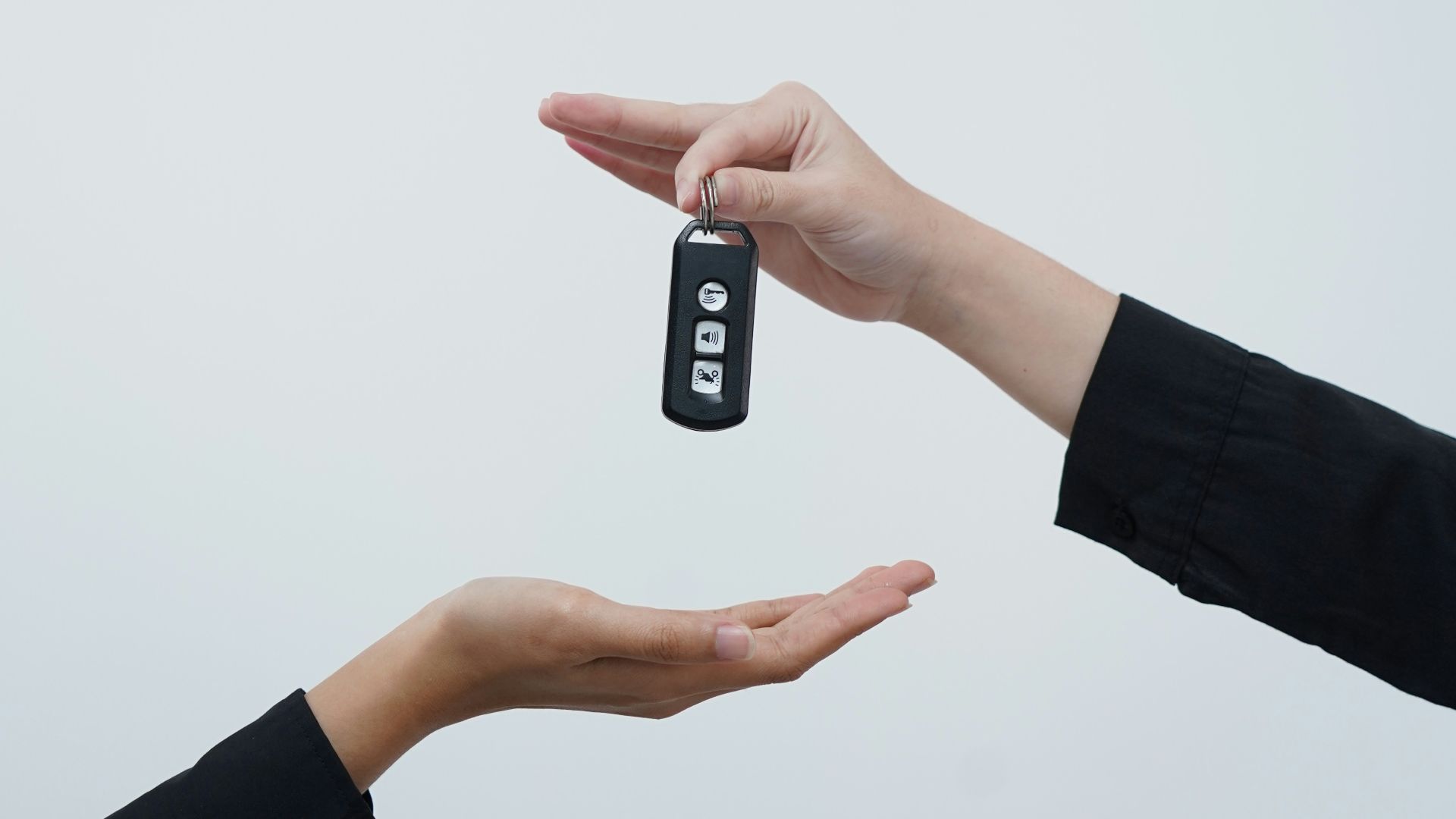 Hands exchanging a car key against a light background