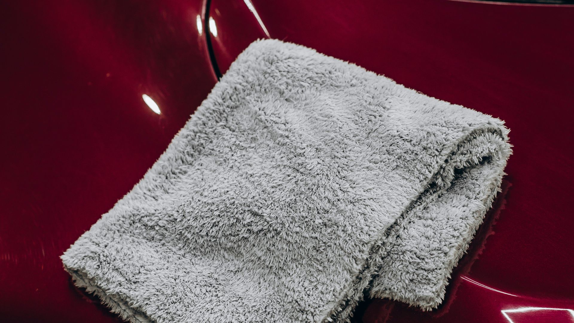 Gray microfiber cloth resting on a red car