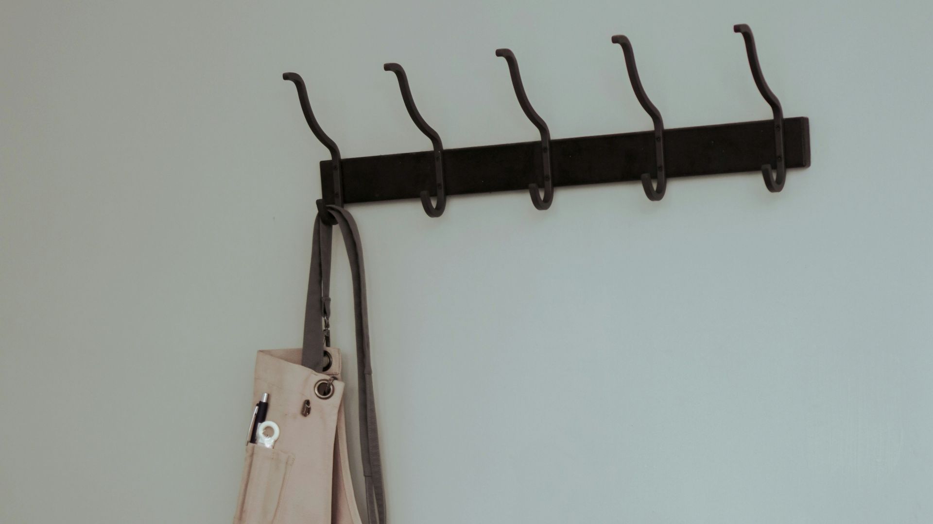 brown leather sling bag hanged on black clothes hanger
