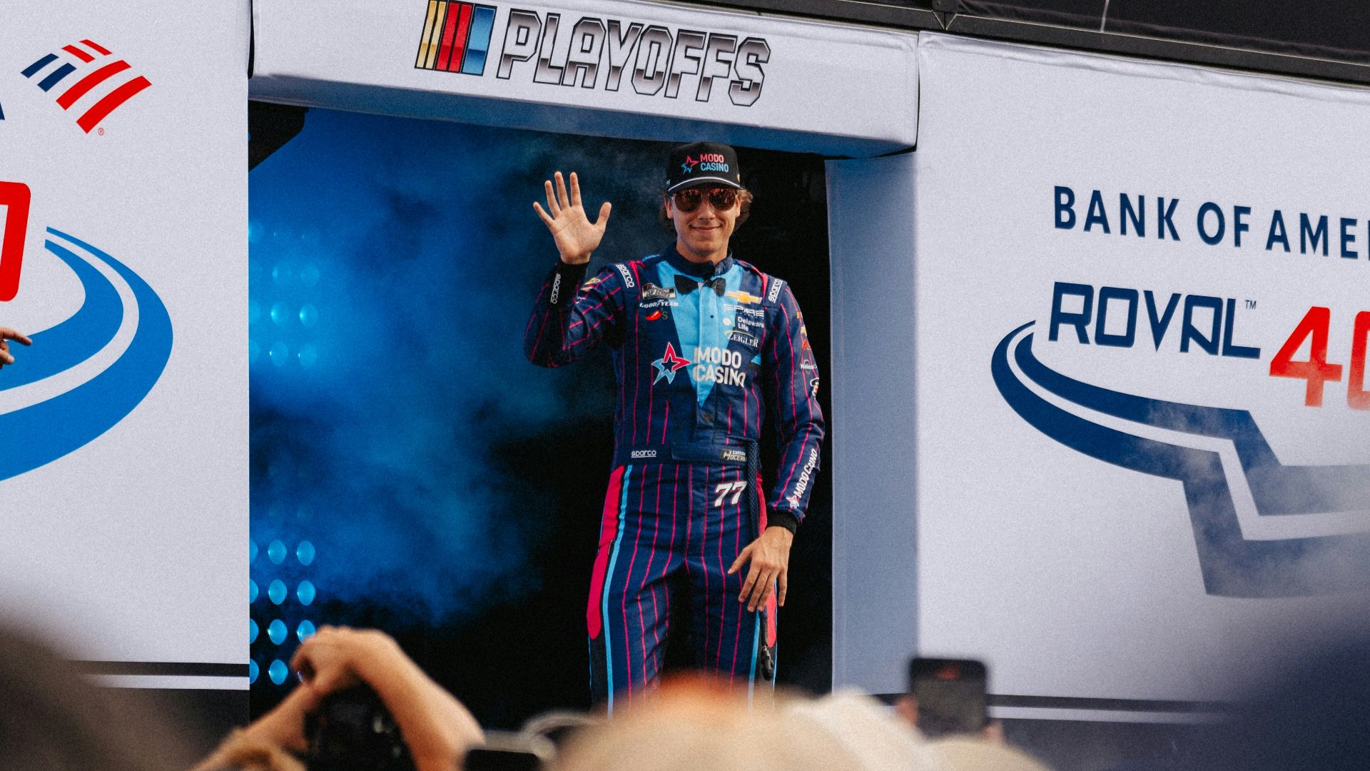 A race car driver waves to the crowd