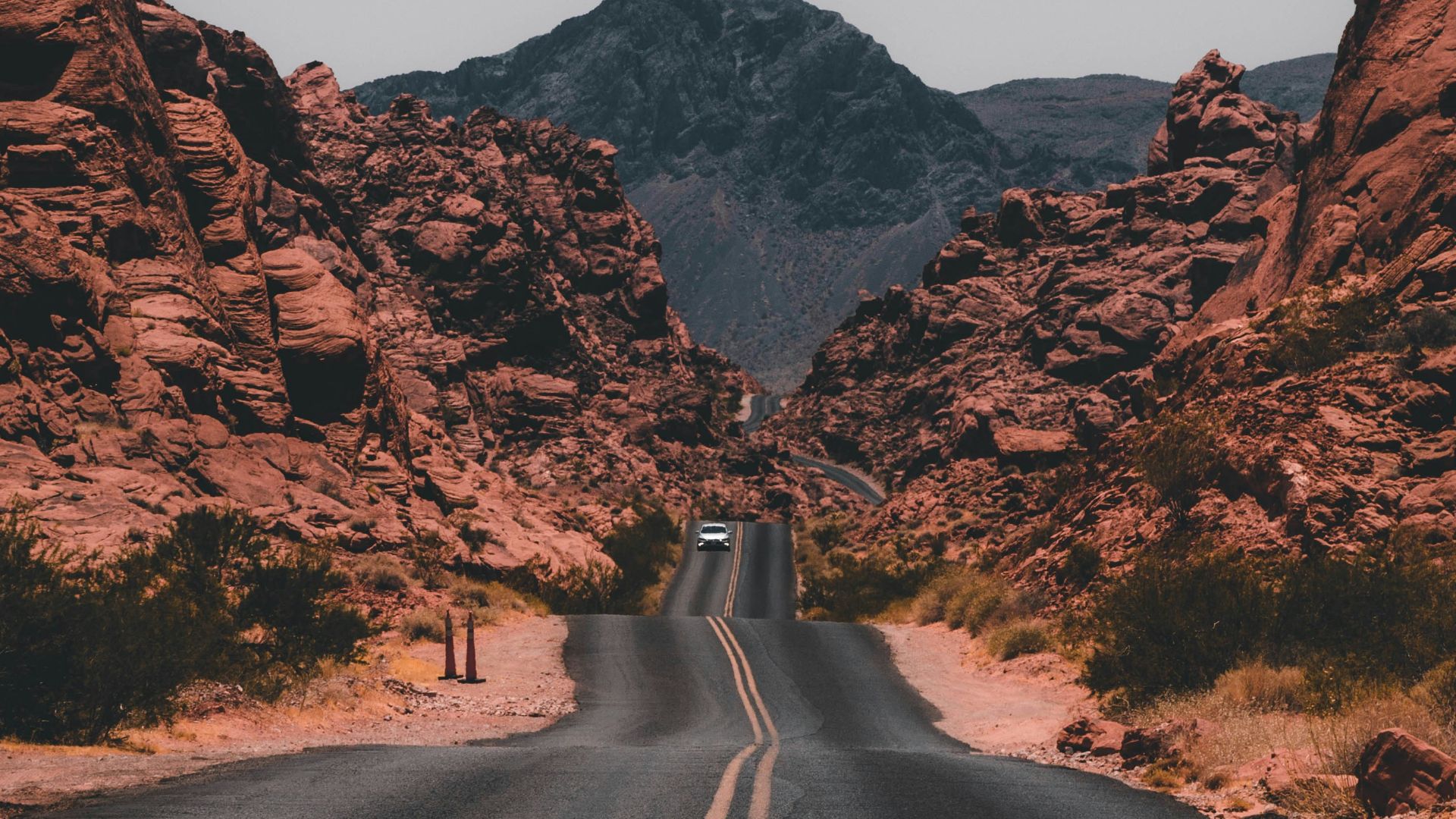black concrete road surrounded by brown rocks