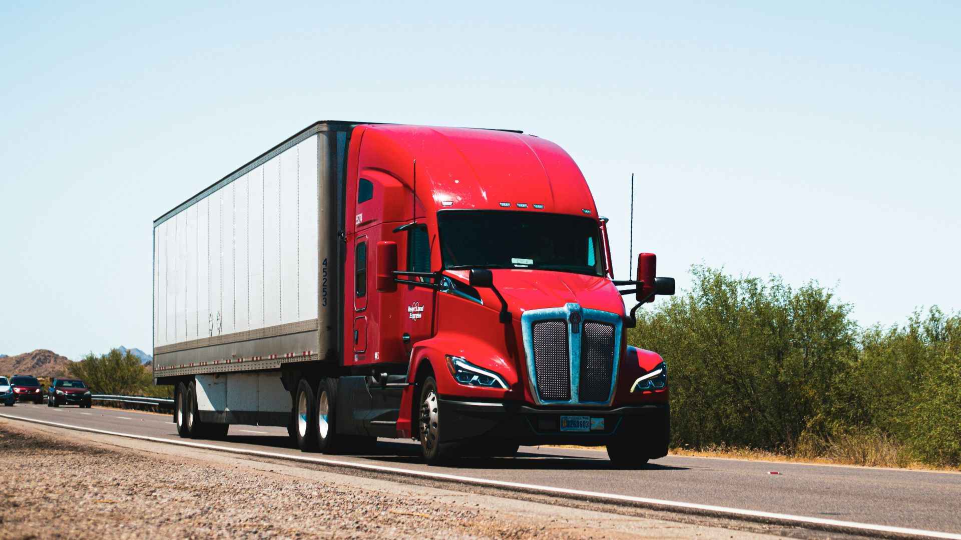 A red semi truck driving down a country road