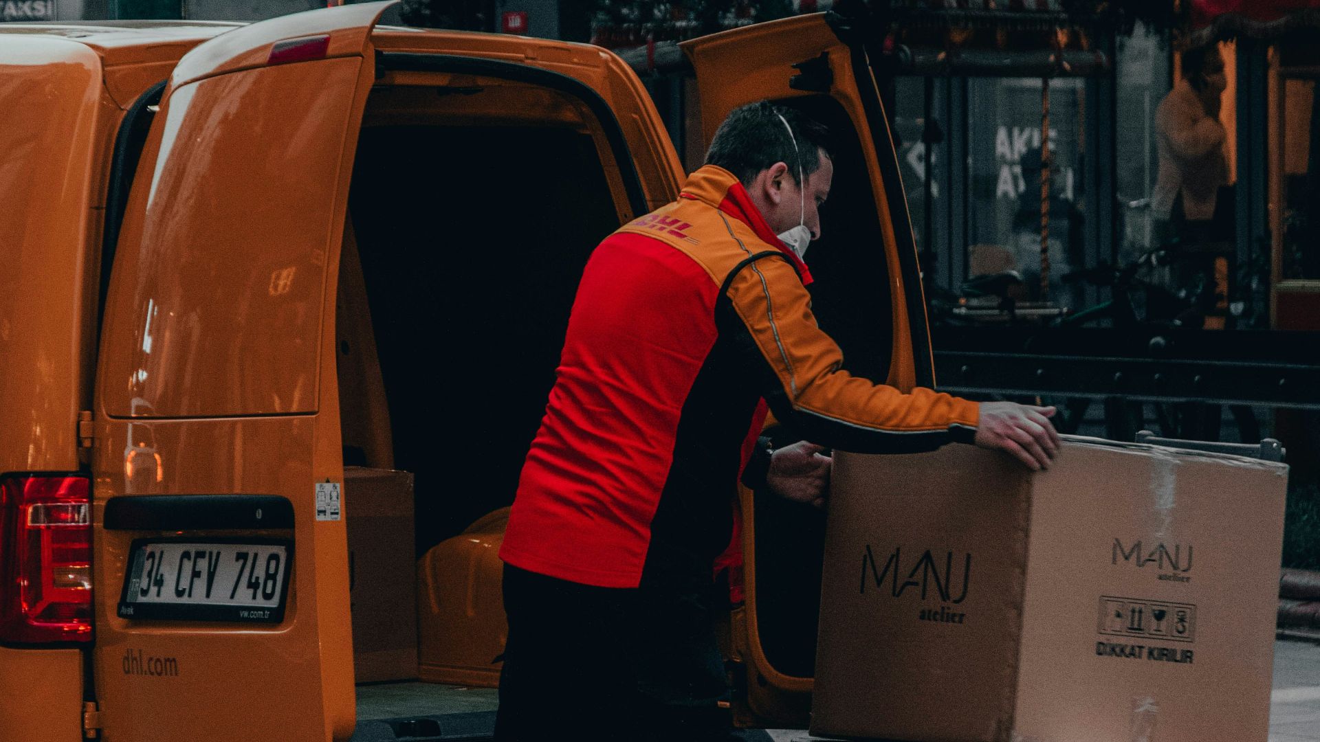 man in red jacket standing beside orange van during daytime