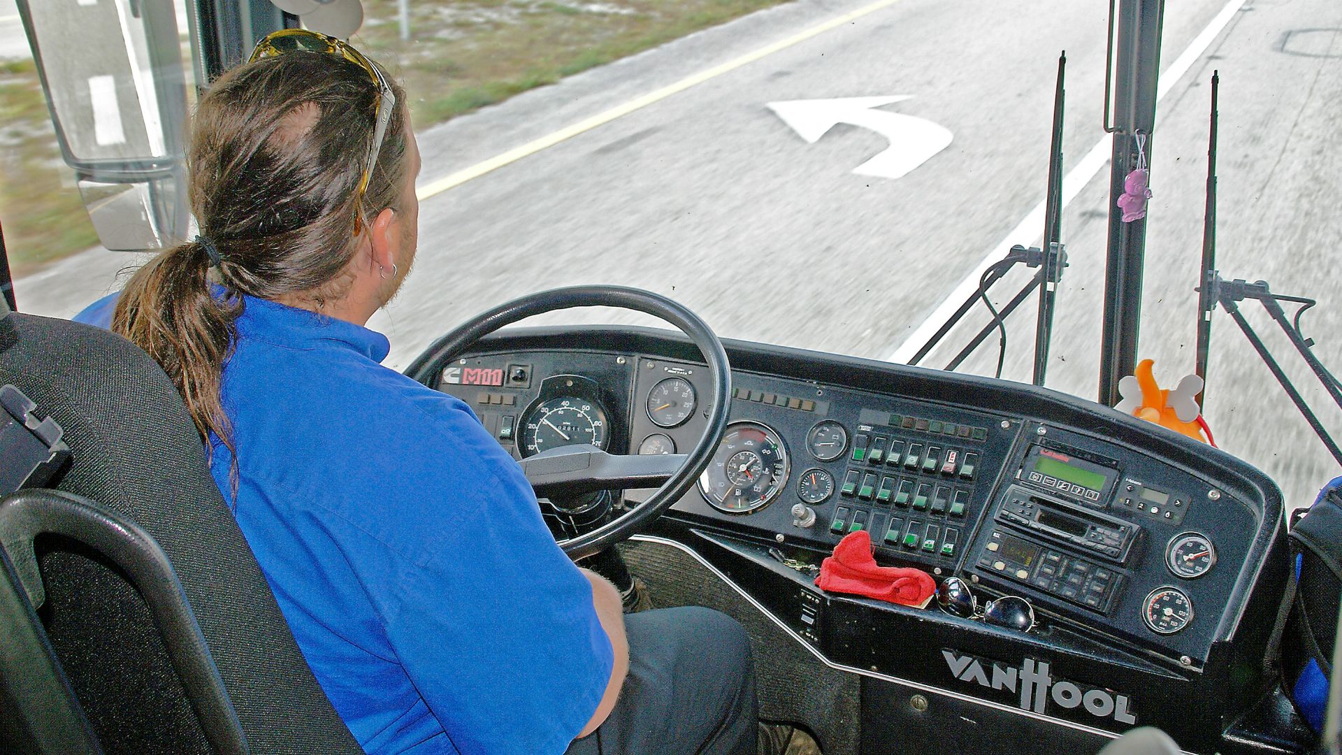 Driver in blue shirt operating a bus dashboard