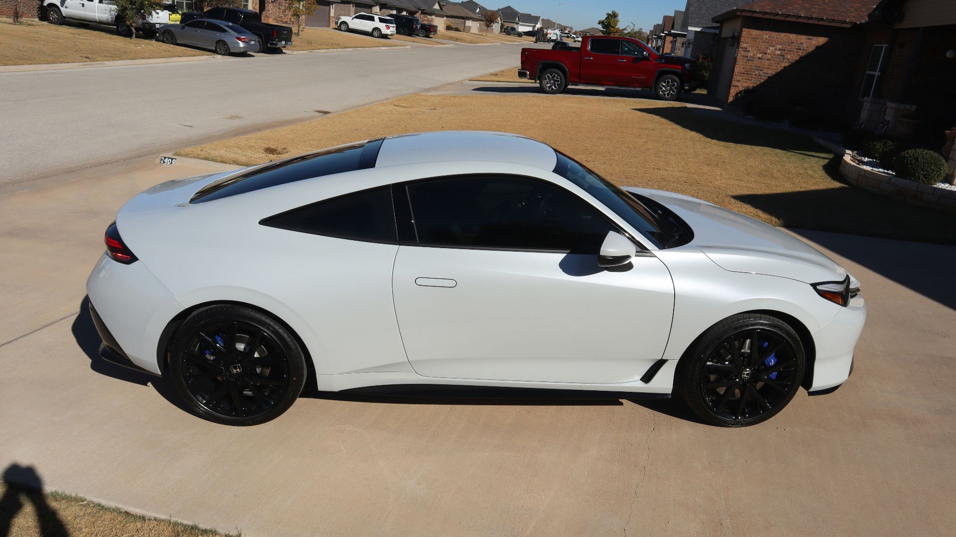 White sports car with black rims parked.
