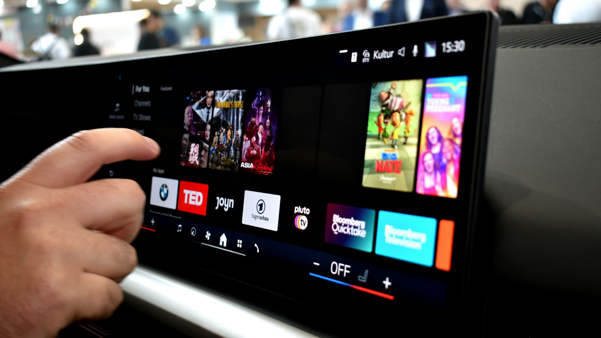 Person touching a car infotainment screen with media options.