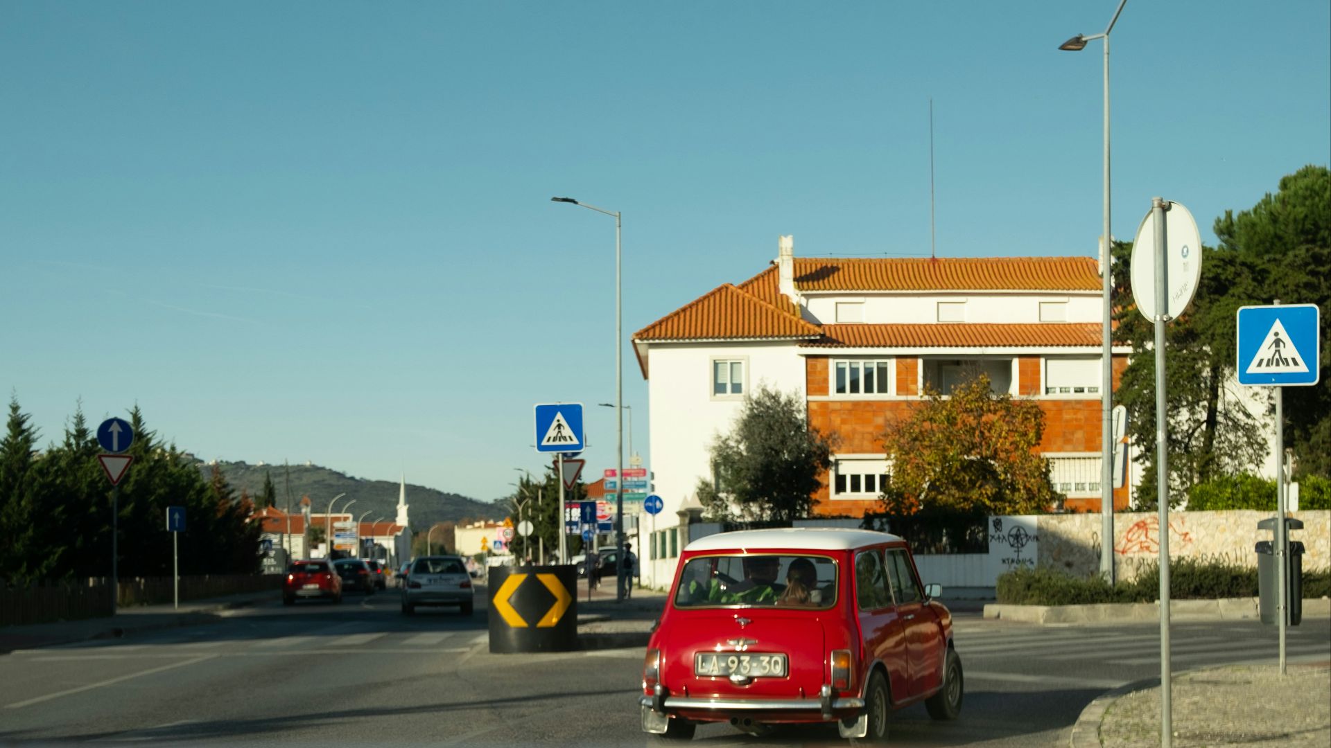 A small red car driving down a street