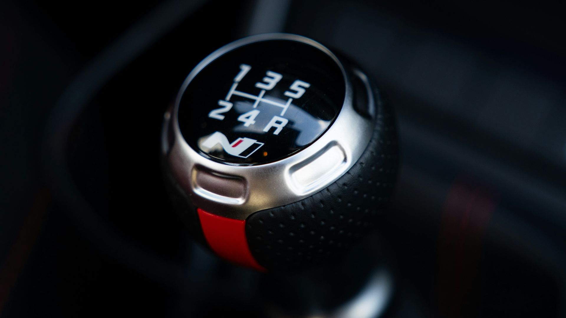 Close-up of a manual car gear shift knob.