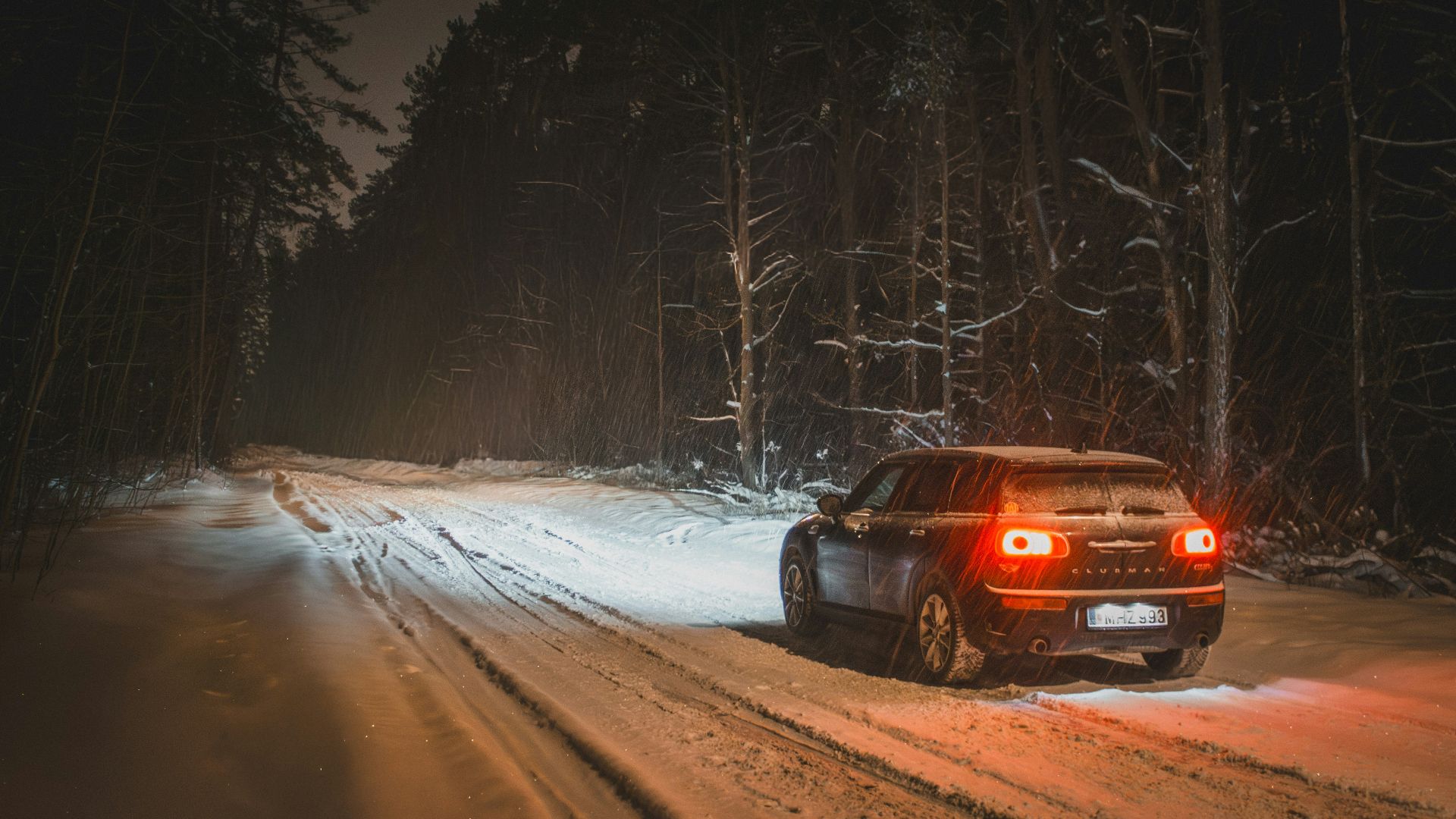 Car driving on snowy forest road at night
