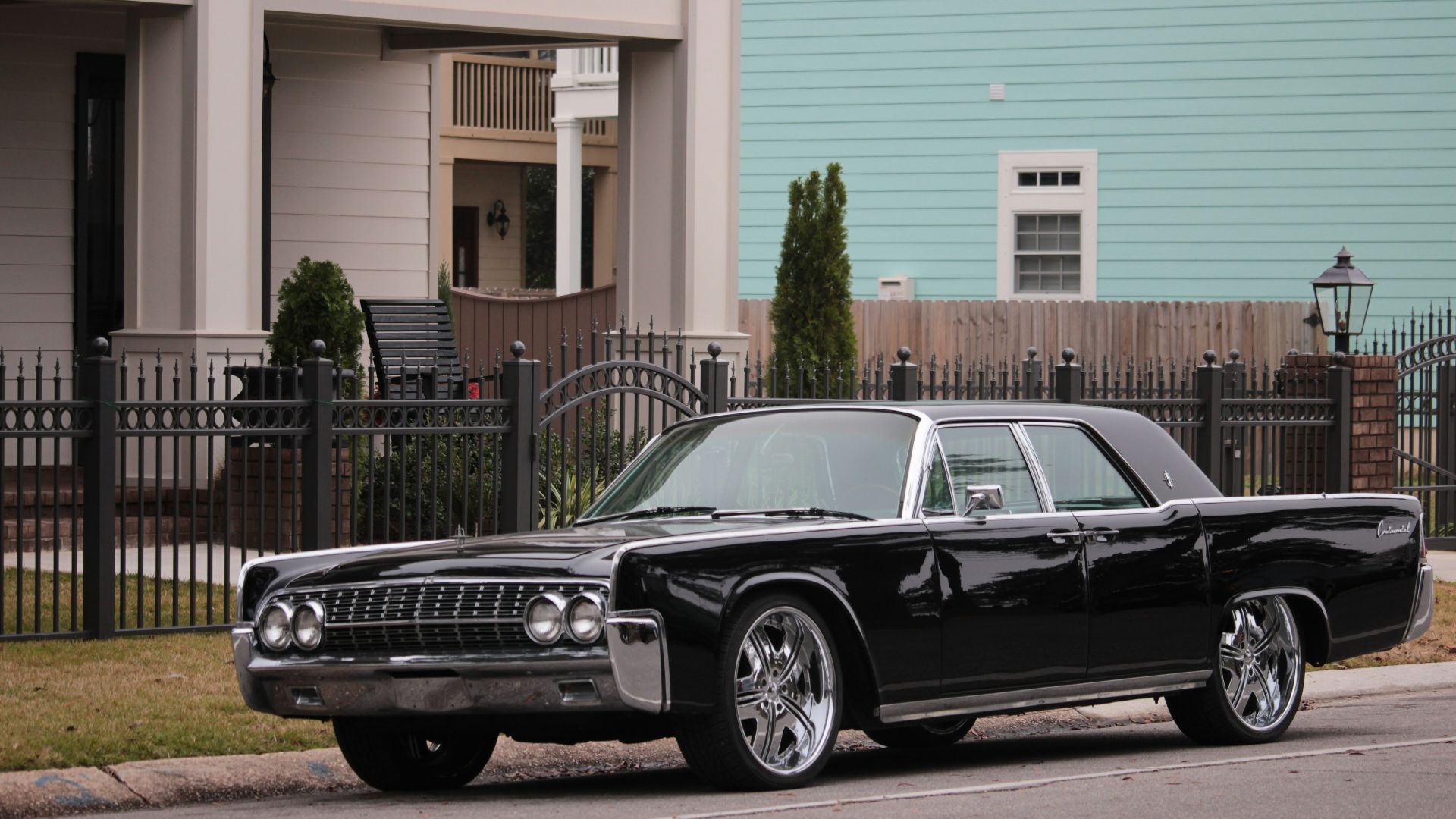 black sedan parked in front of white and pink building