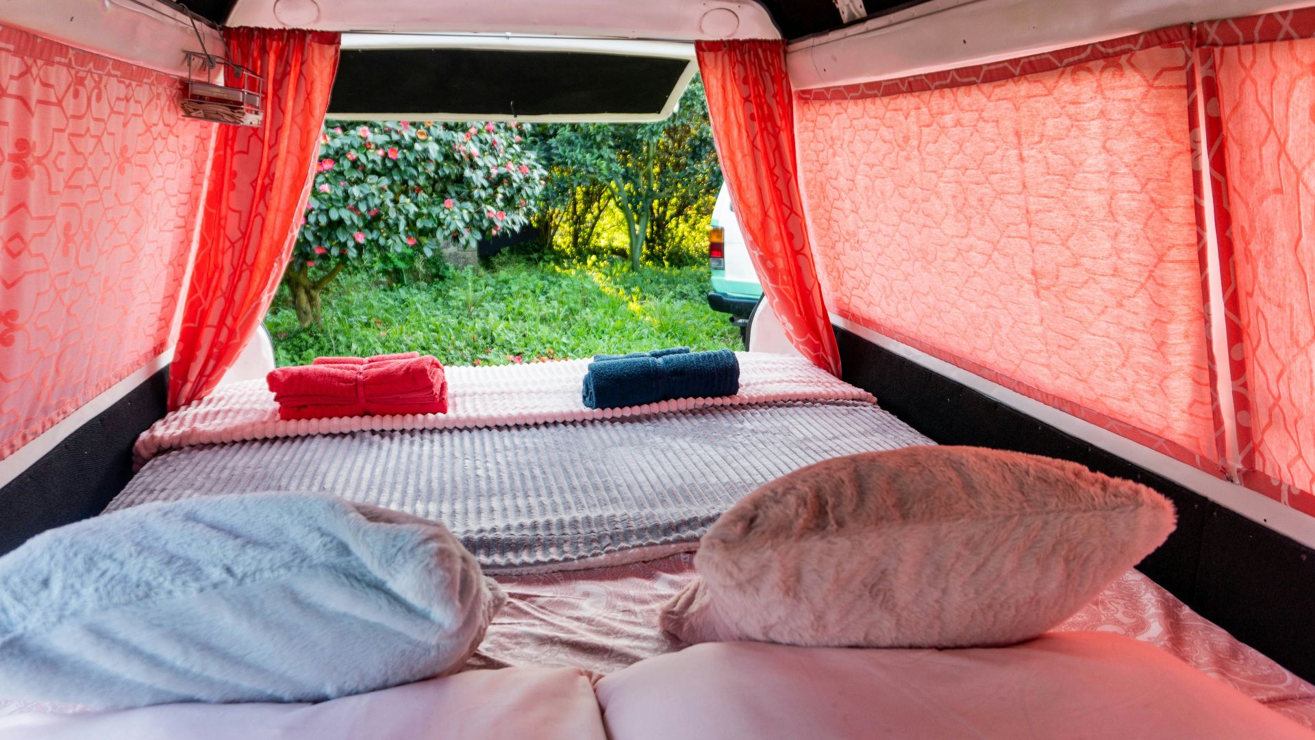 A bed in a small room with red curtains