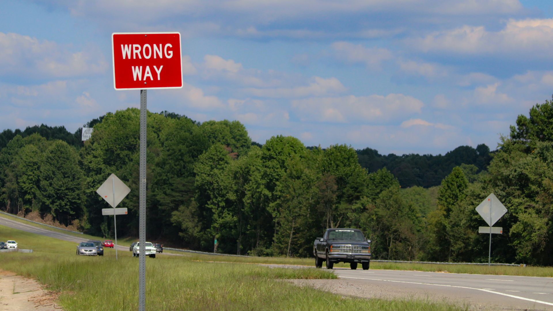 A red wrong way sign sitting on the side of a road