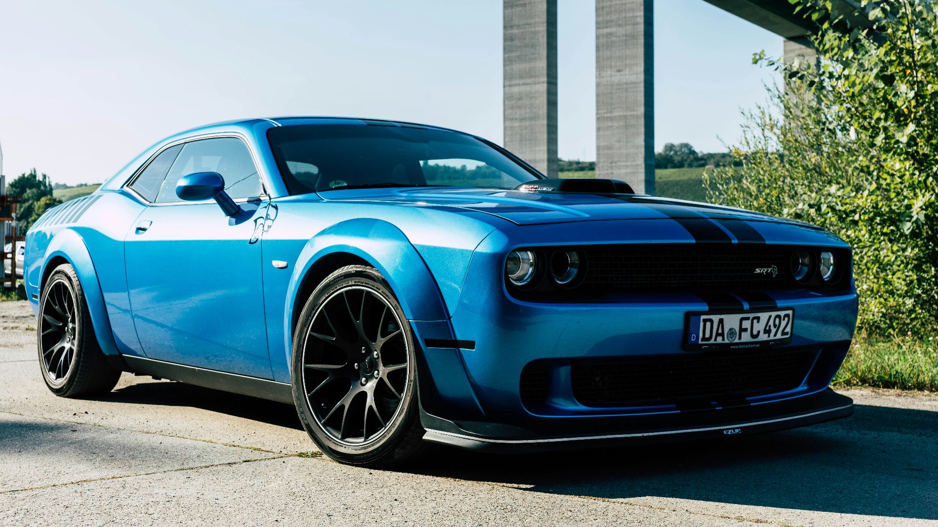 a blue sports car parked in front of a bridge