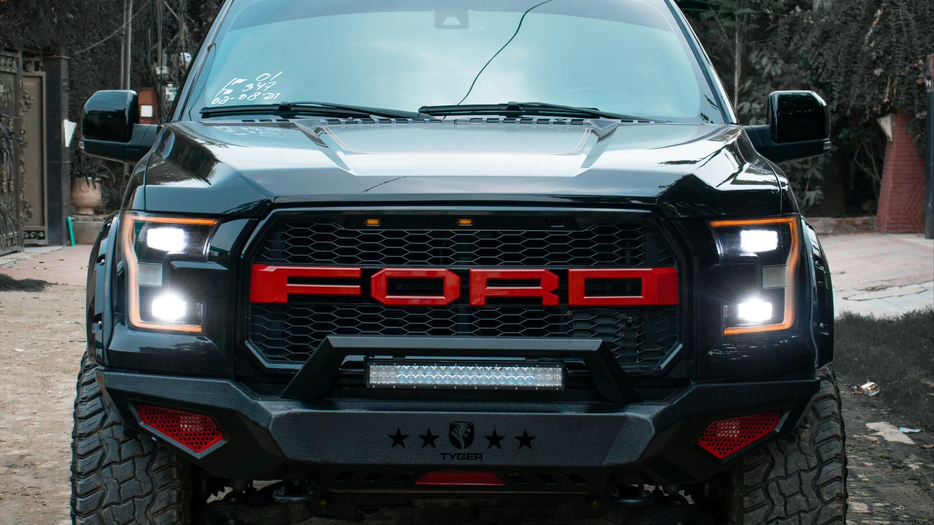 the front of a black truck parked on a cobblestone street