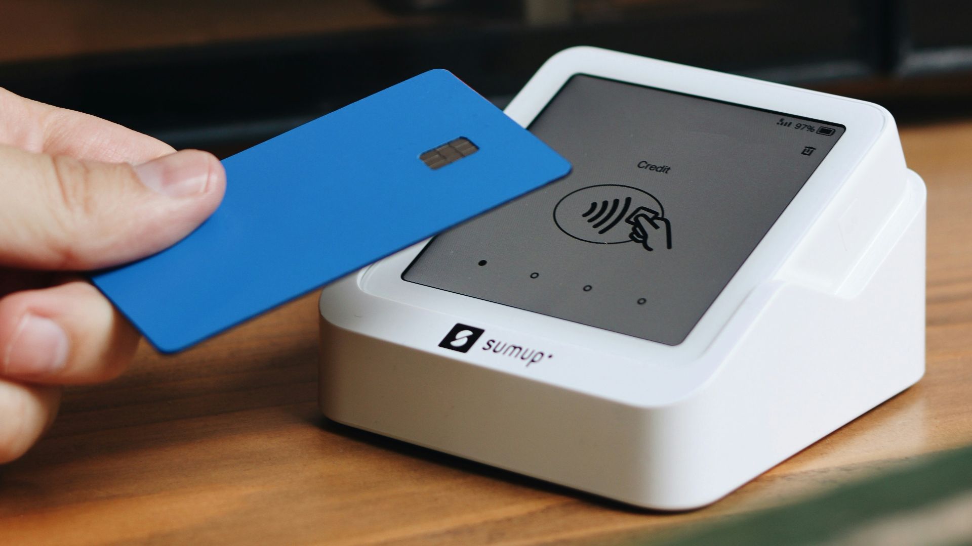 A person holding a blue card in front of a computer