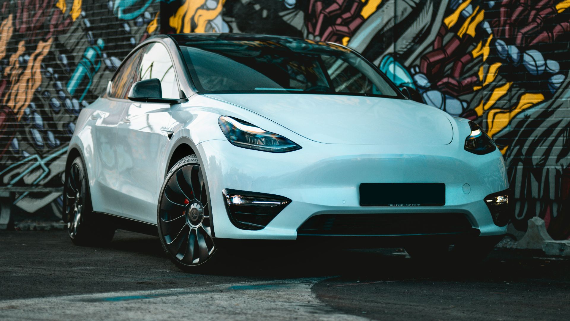 a white car parked in front of a graffiti covered wall