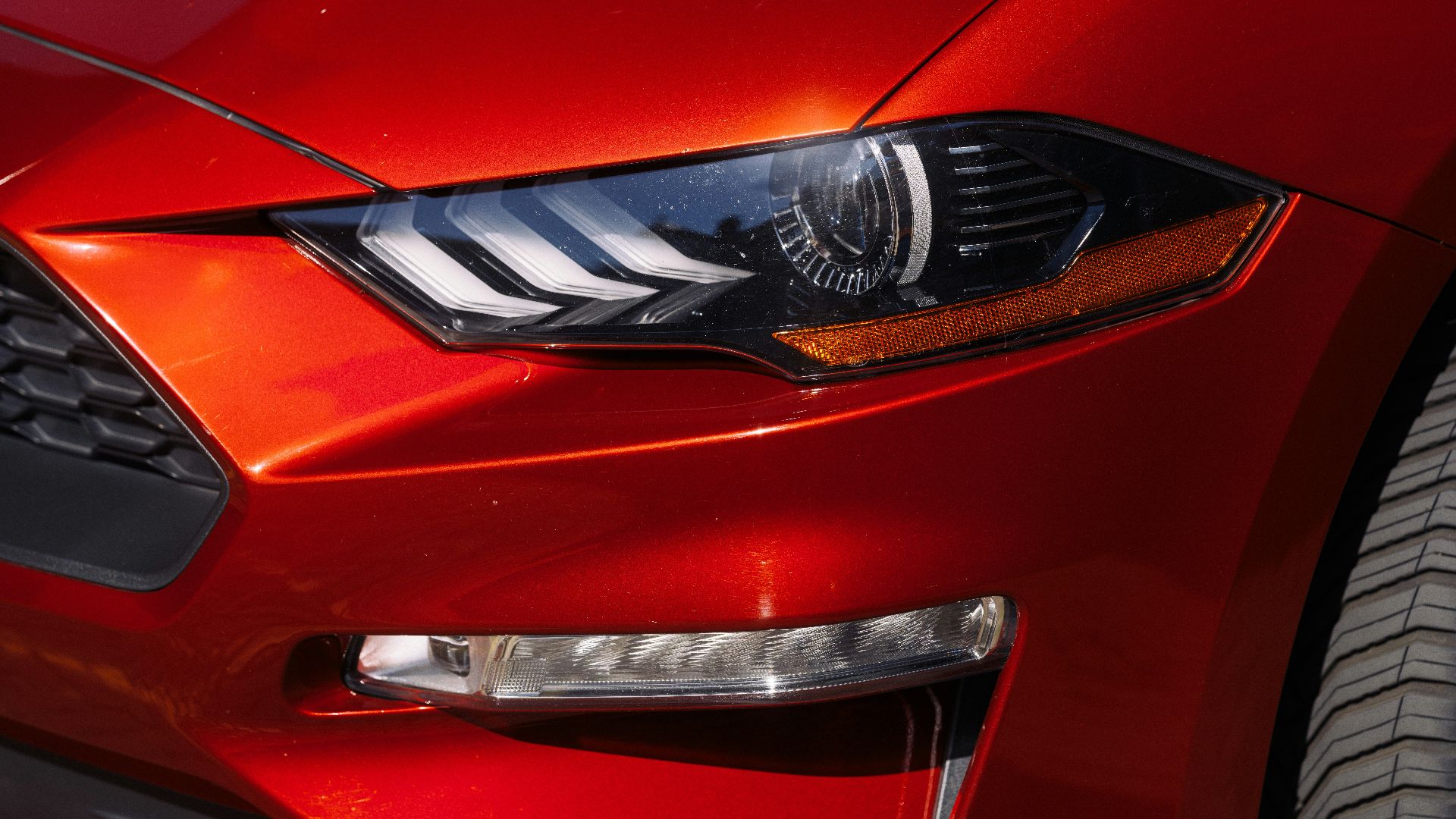 A close-up shows a red mustang headlight.
