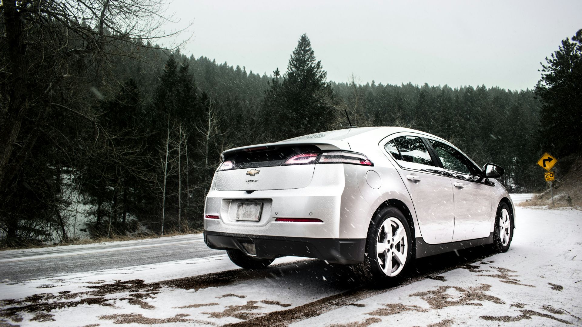 silver Chevrolet sedan on roadway near green leaf trees