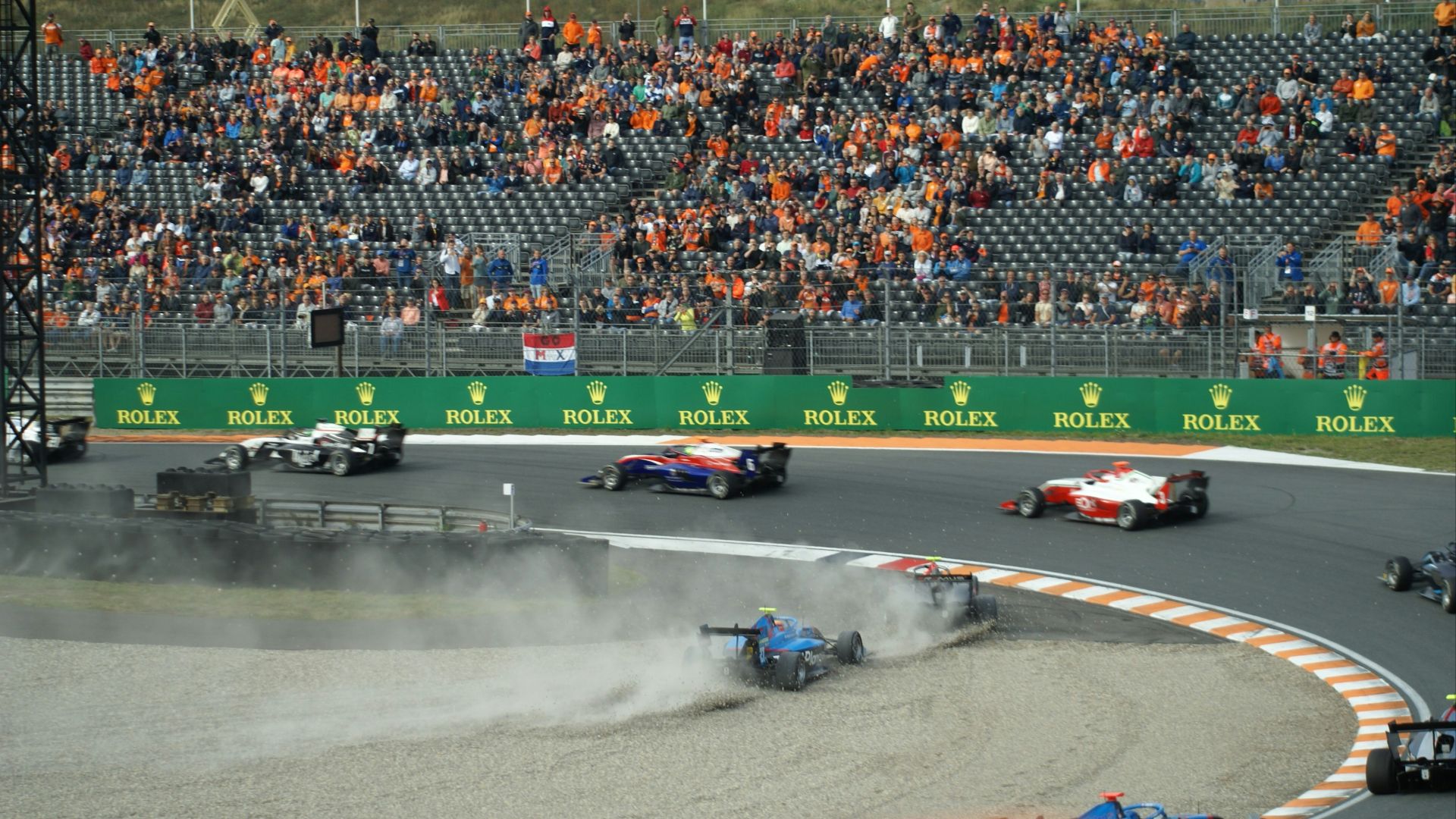 a group of race cars on a track with a crowd watching